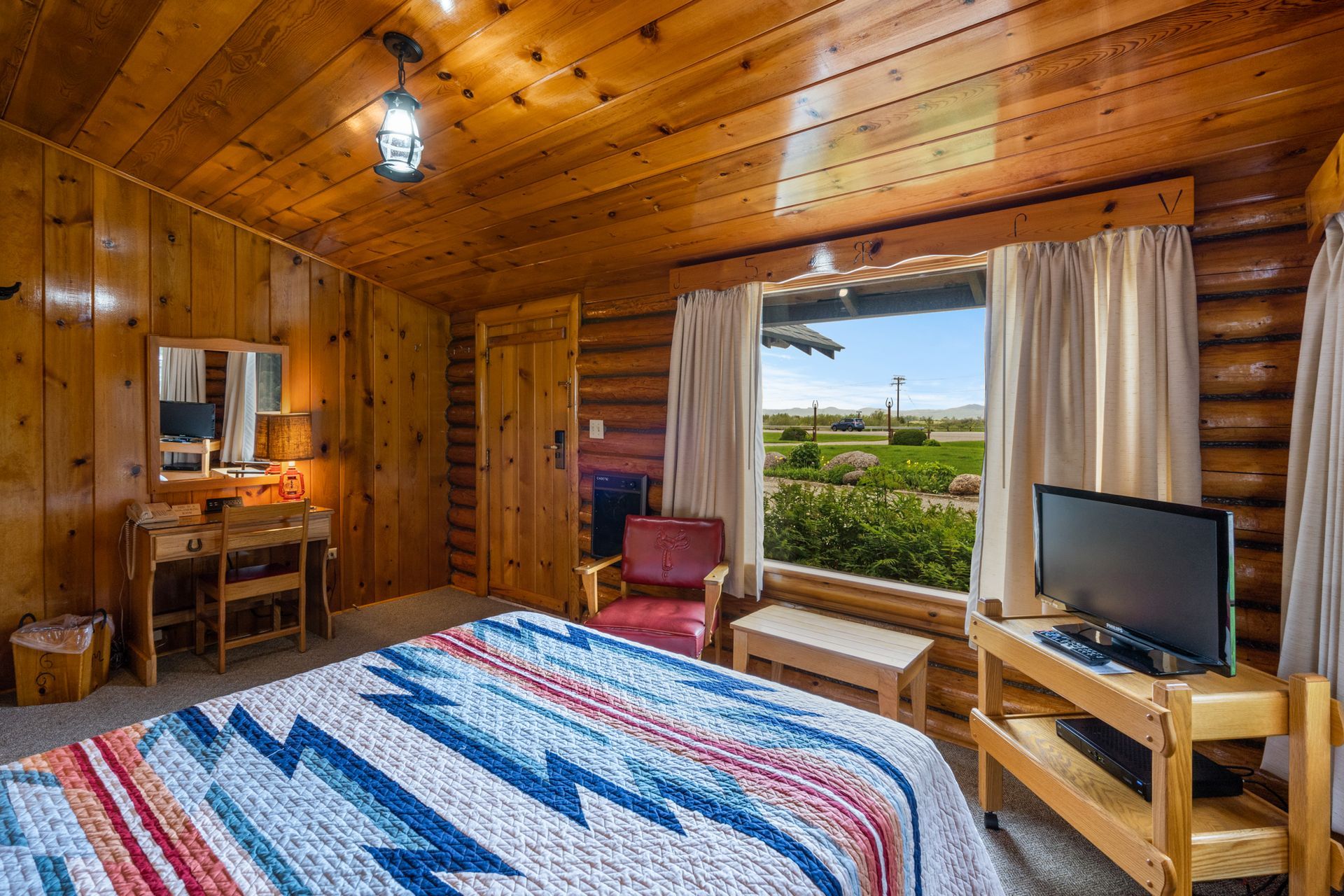 A bedroom in a log cabin with a king size bed and a flat screen tv.