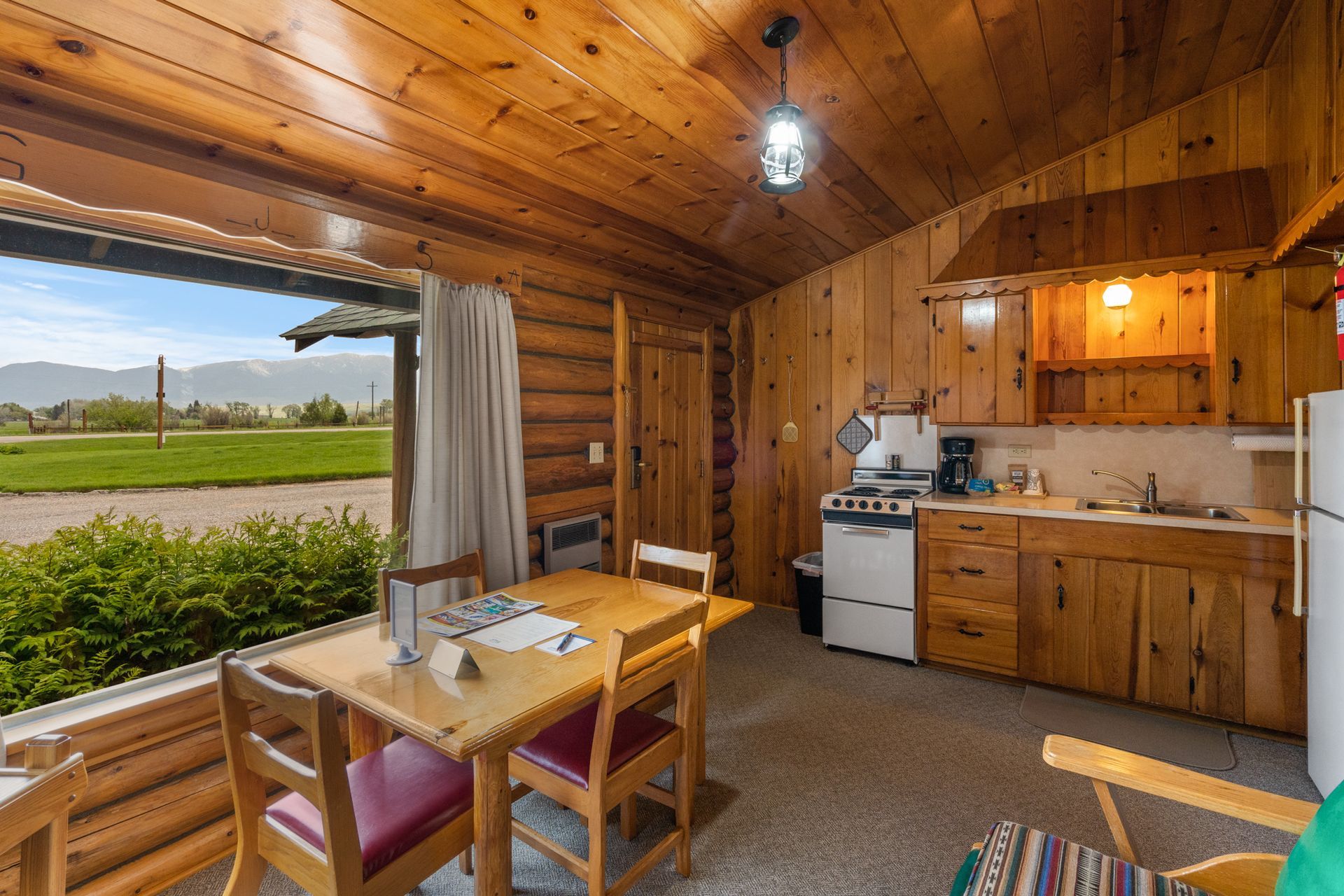 A log cabin with a dining table and chairs and a kitchen.