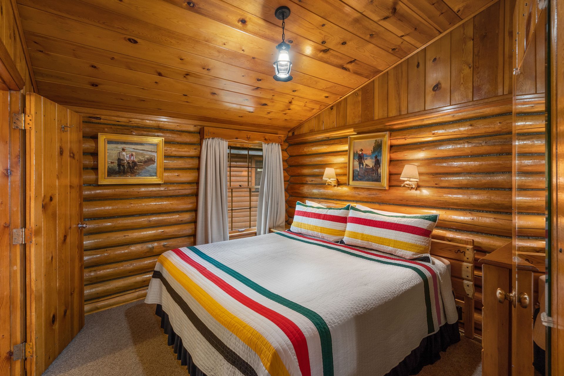 A bedroom in a log cabin with a king size bed and a striped blanket.