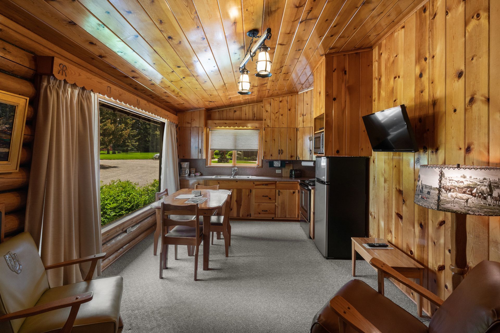 A living room in a log cabin with a table and chairs