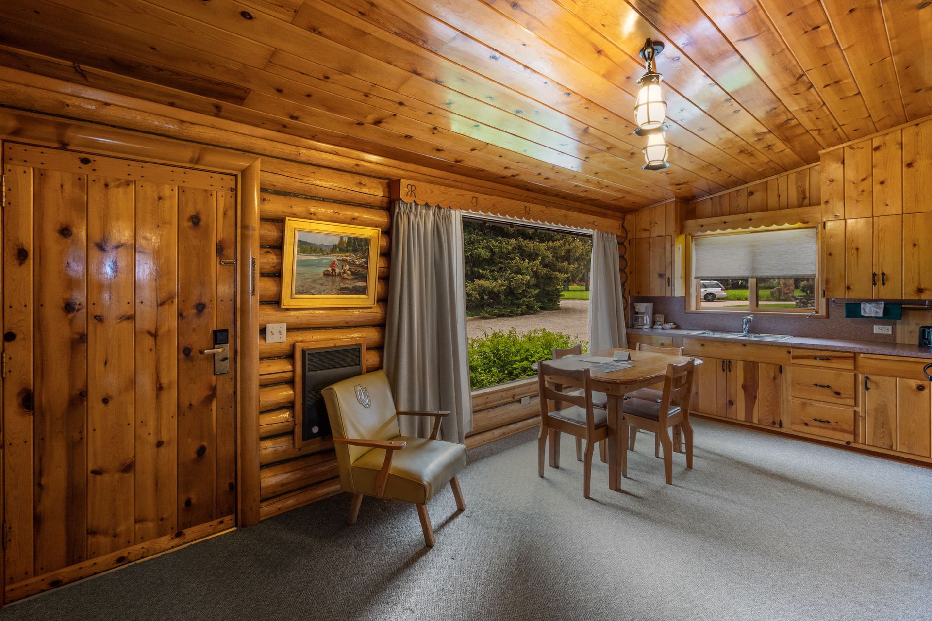 A living room in a log cabin with a table and chairs.