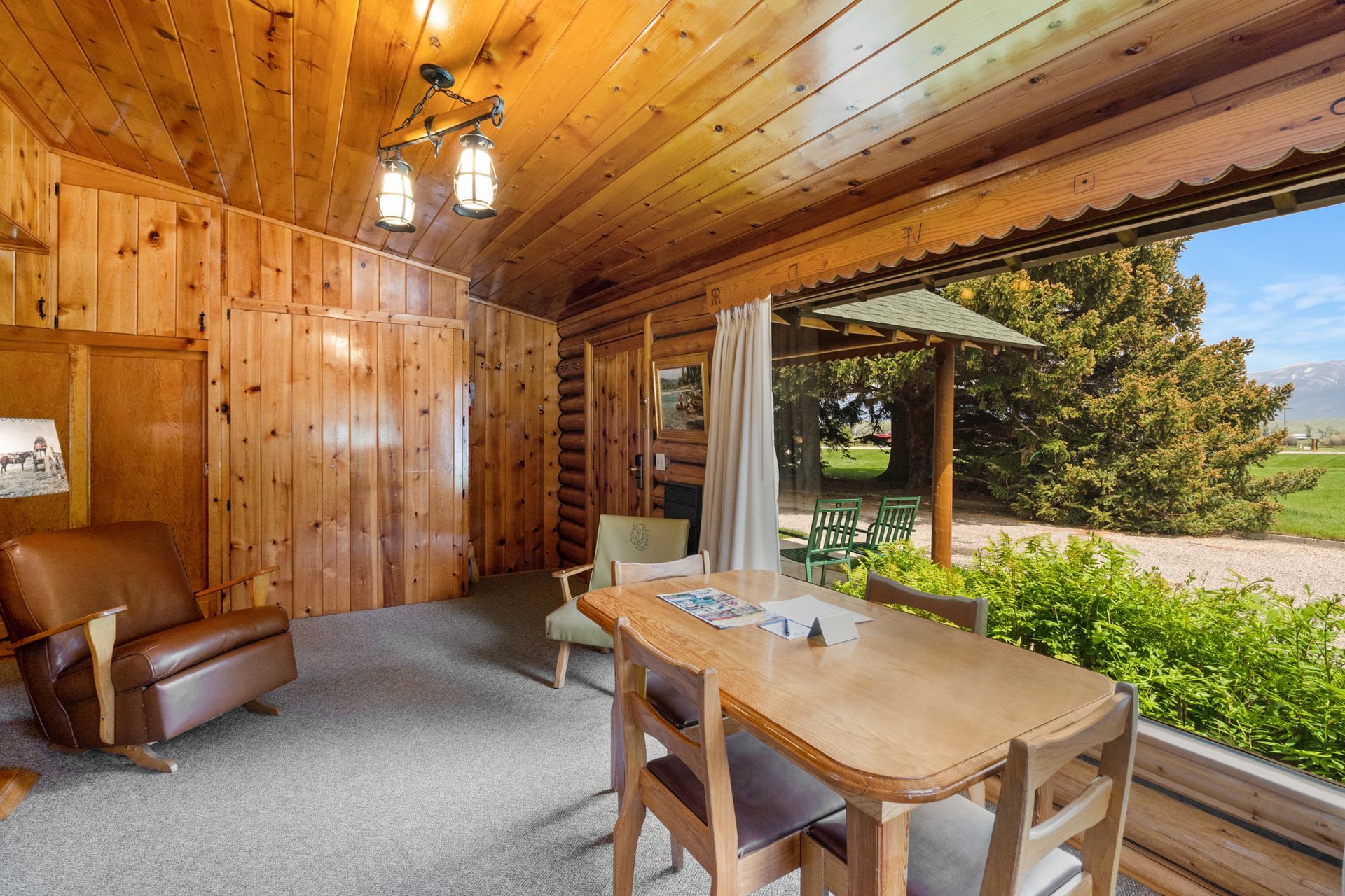 A living room with a table and chairs in a log cabin.