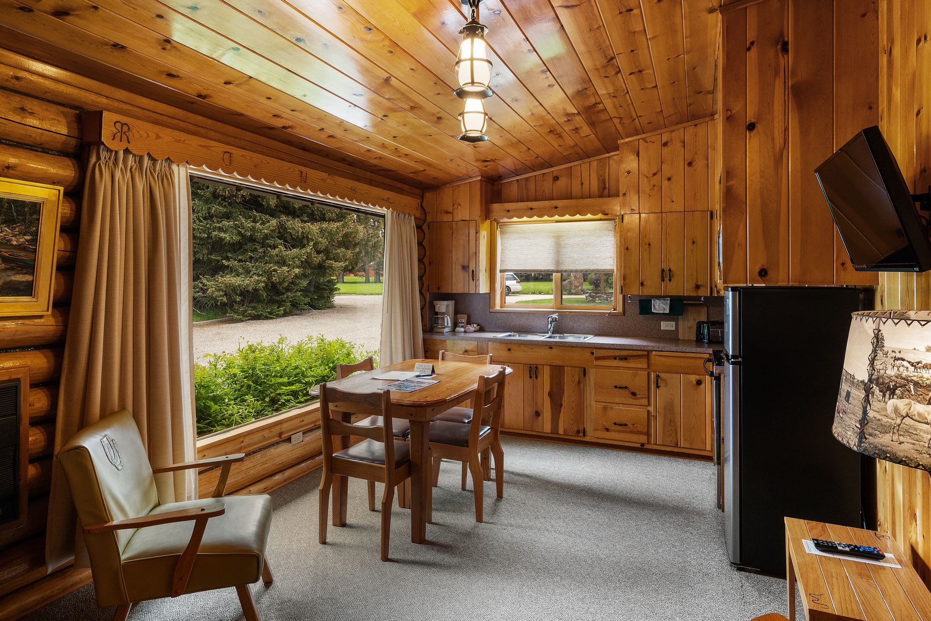 A log cabin with a table and chairs and a black refrigerator