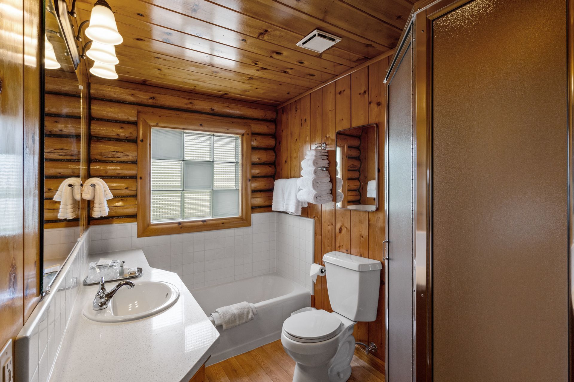 A bathroom in a log cabin with a toilet , sink and bathtub.