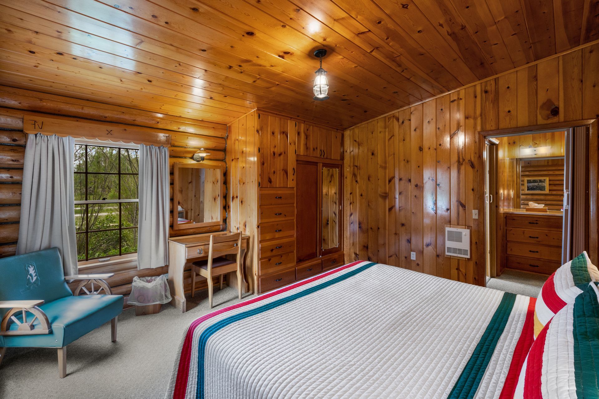 A bedroom in a log cabin with a king size bed and a chair.