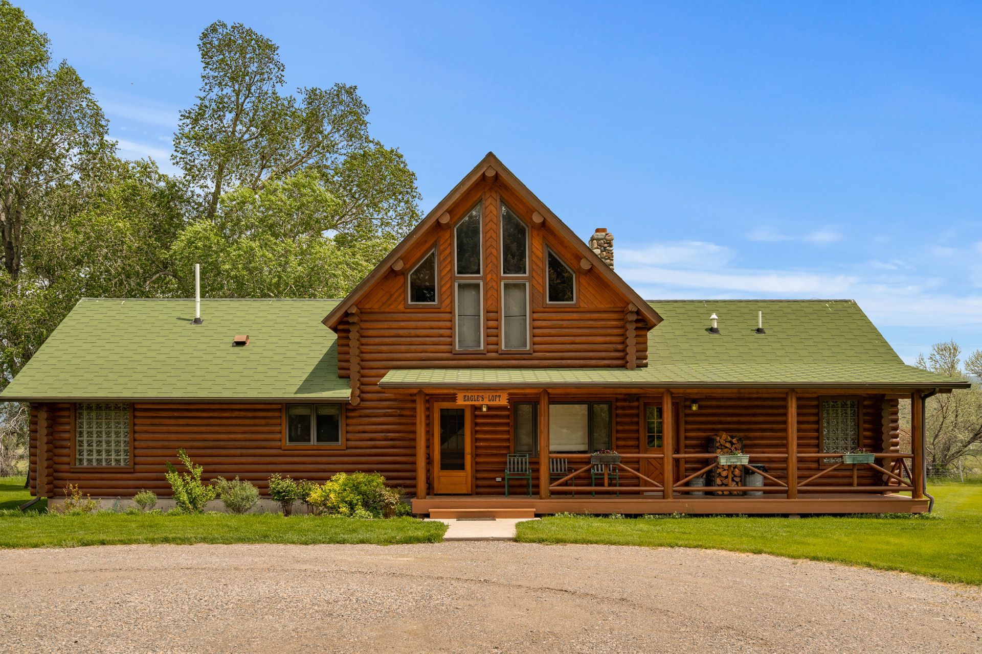 A large log cabin with a green roof and a porch