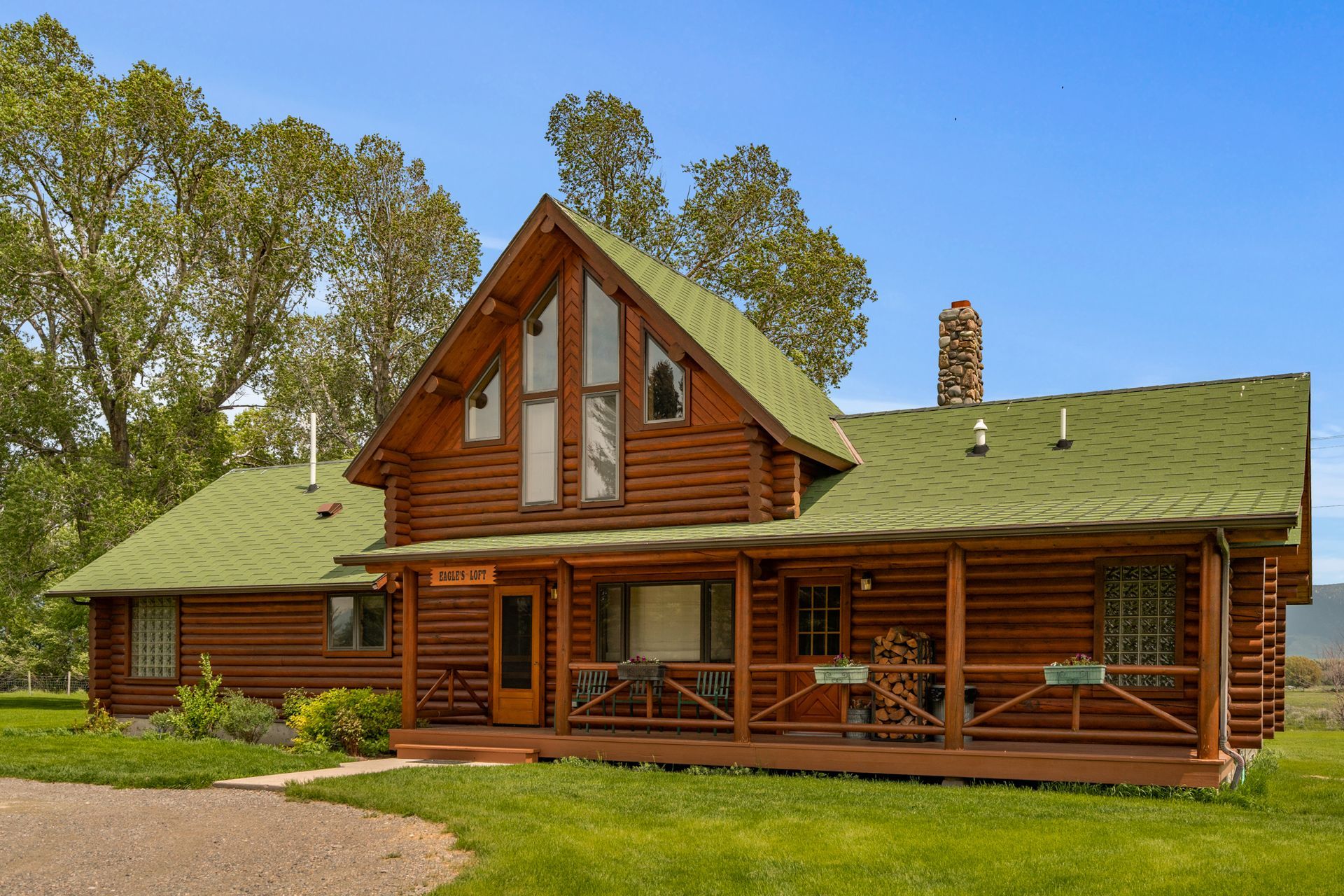 A large log cabin with a green roof and a large porch