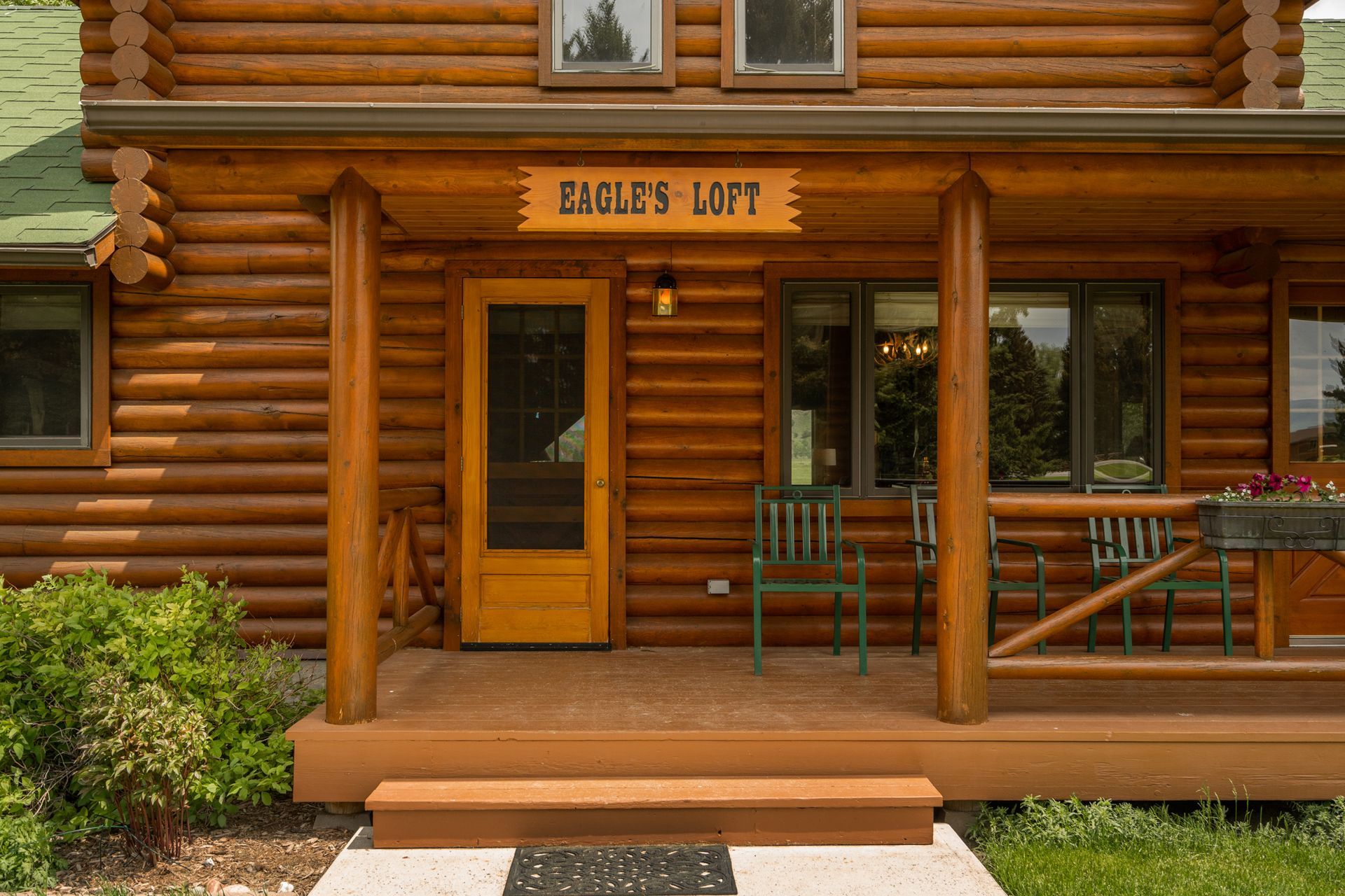 The front porch of a log cabin with a sign that says `` eagle 's loft ''.