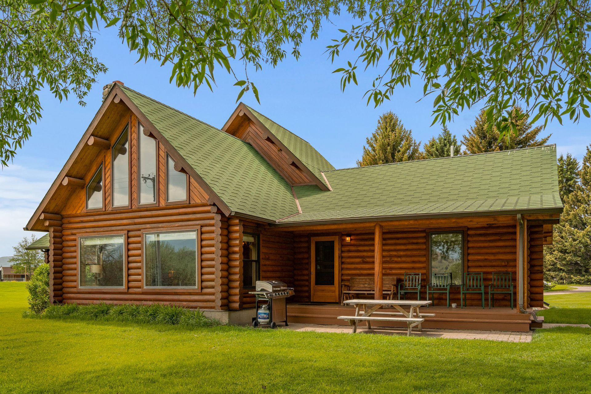 A log cabin with a green roof and a picnic table