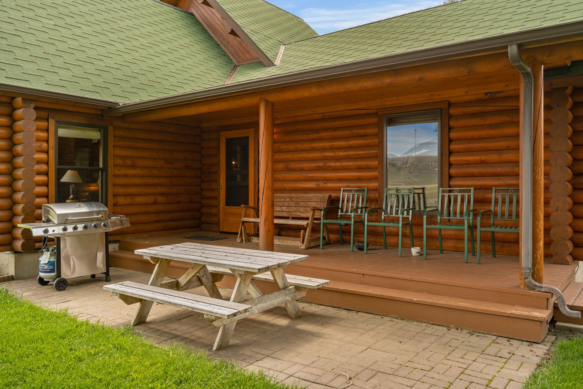 A log cabin with a picnic table and chairs on the porch.