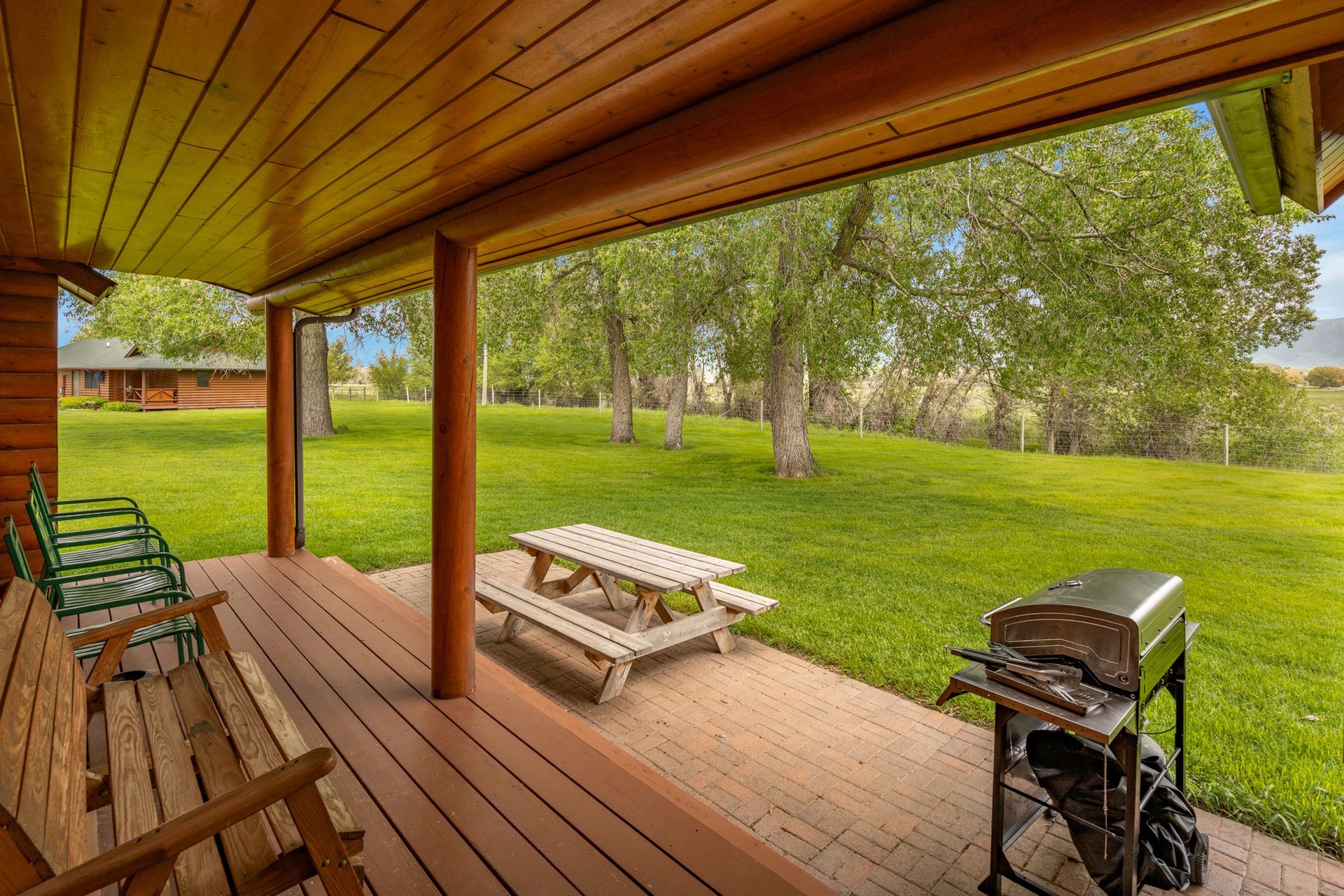 A wooden porch with a picnic table and a grill.