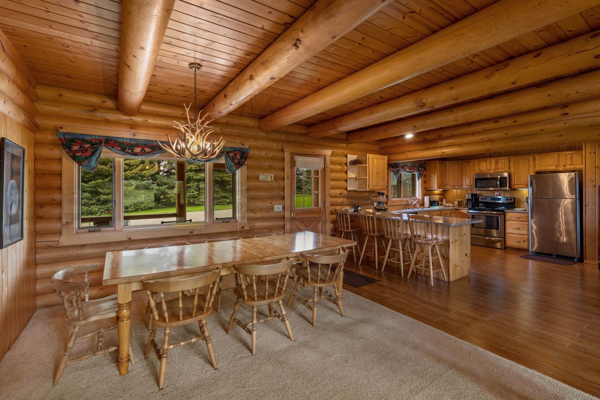 A log cabin with a dining room table and chairs and a kitchen.