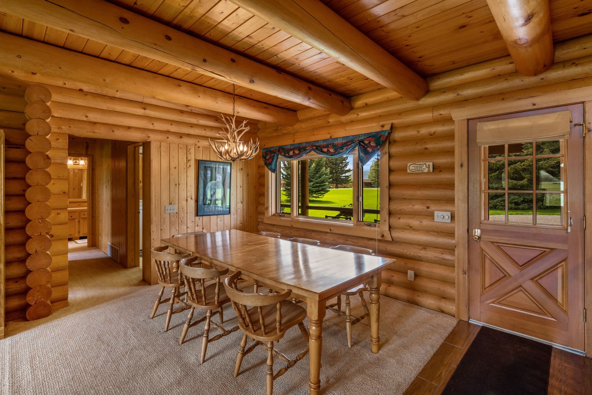 A dining room in a log cabin with a table and chairs.