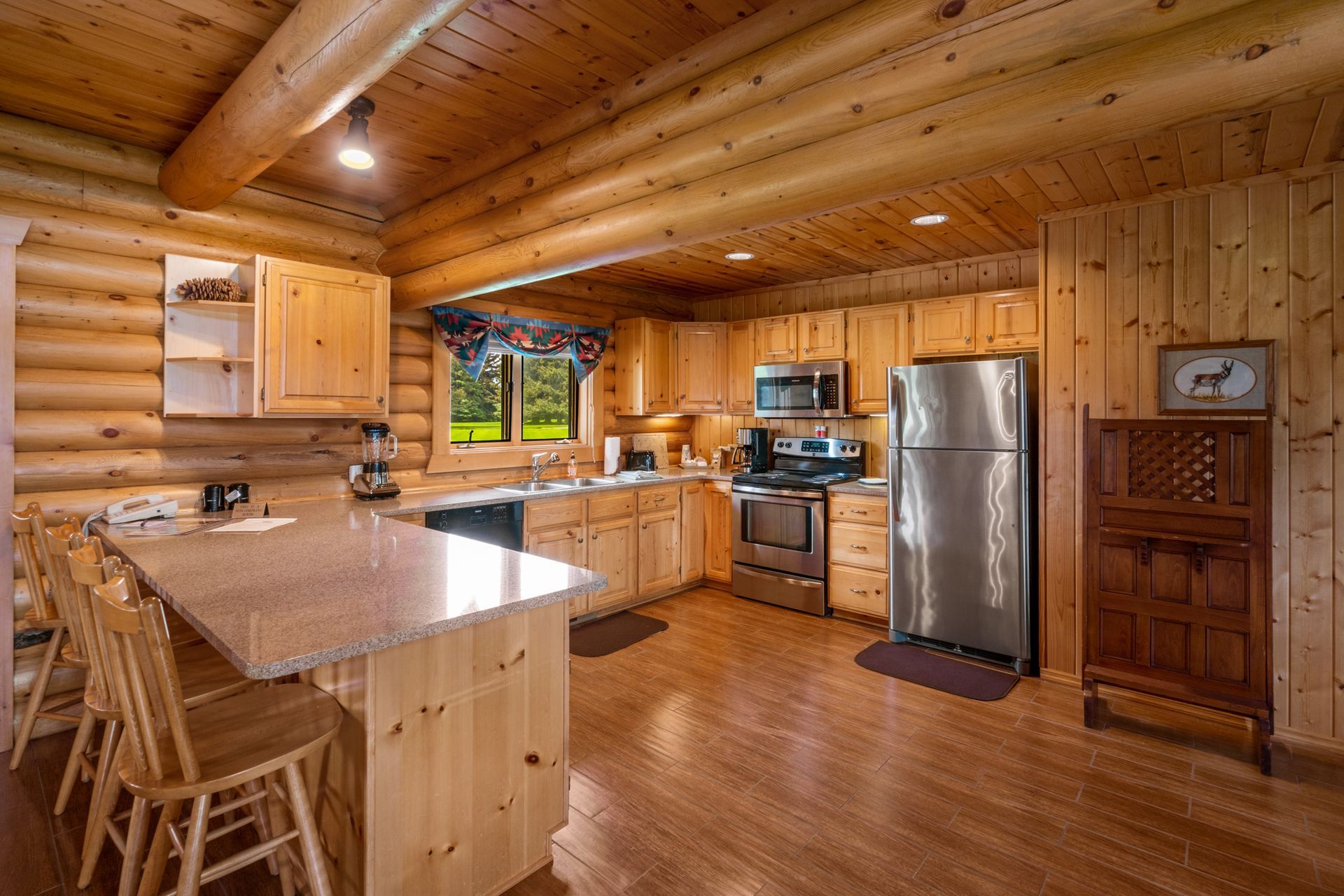 A kitchen in a log cabin with stainless steel appliances and granite counter tops.