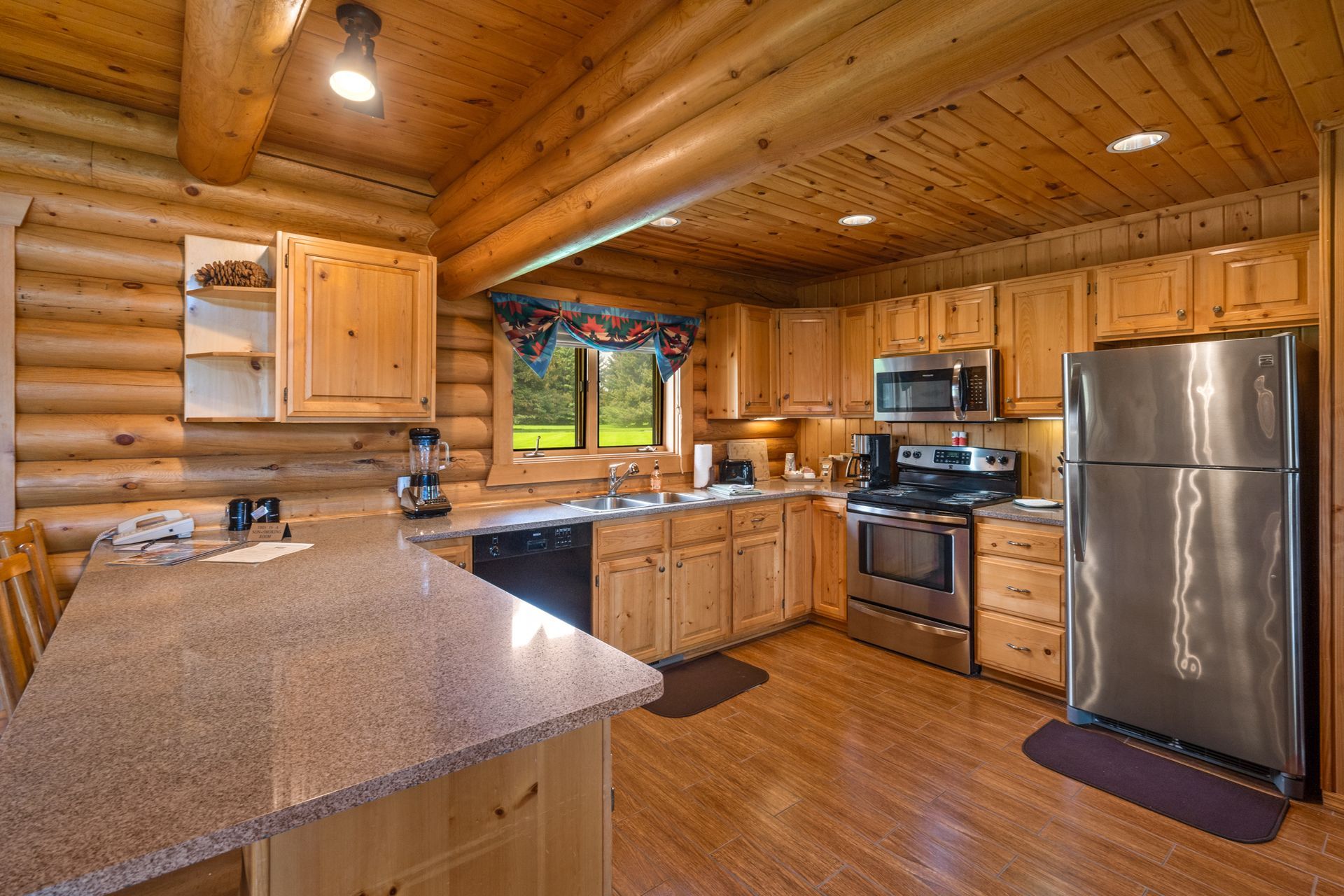 A kitchen in a log cabin with stainless steel appliances and granite counter tops.