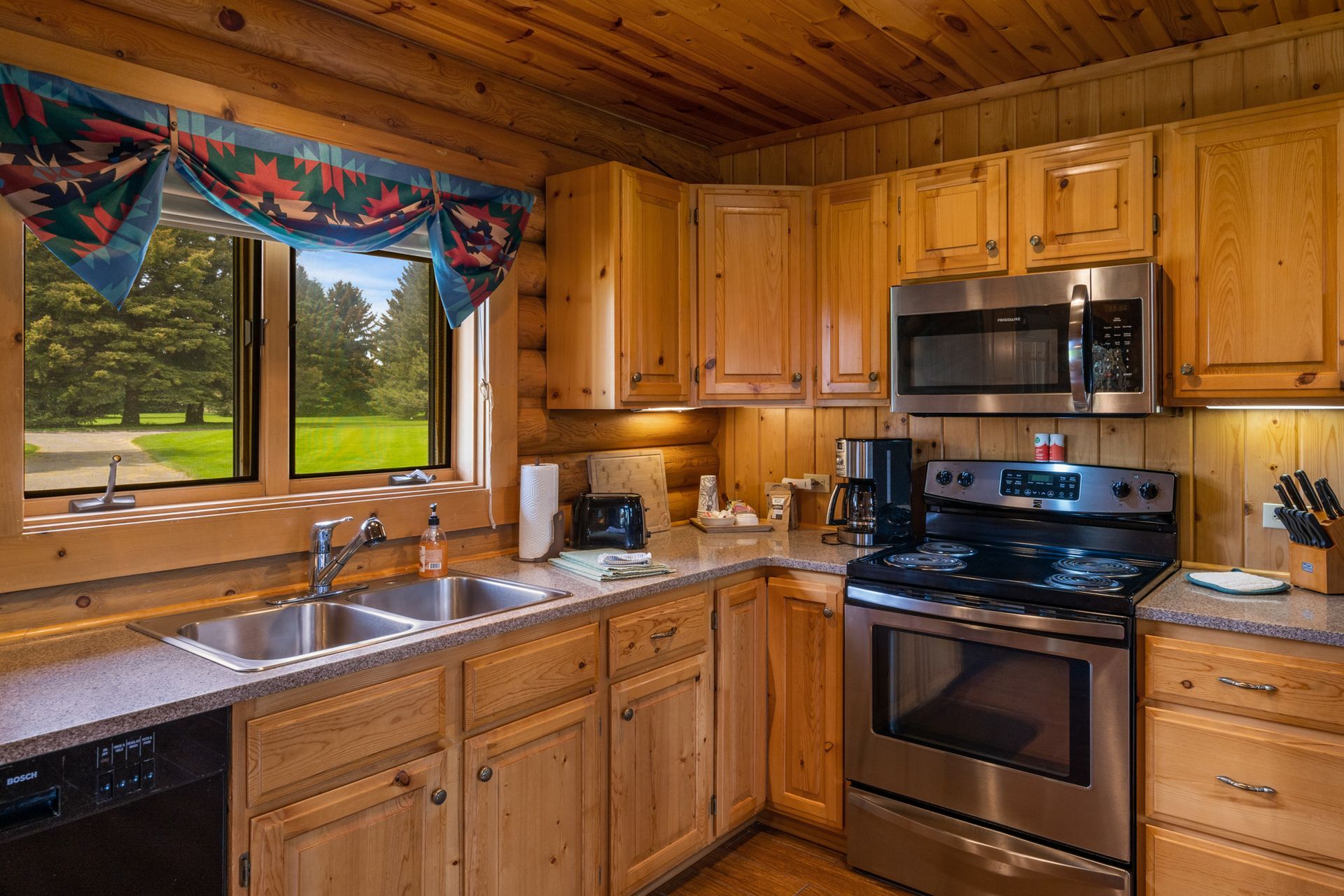 A kitchen in a log cabin with stainless steel appliances and wooden cabinets.