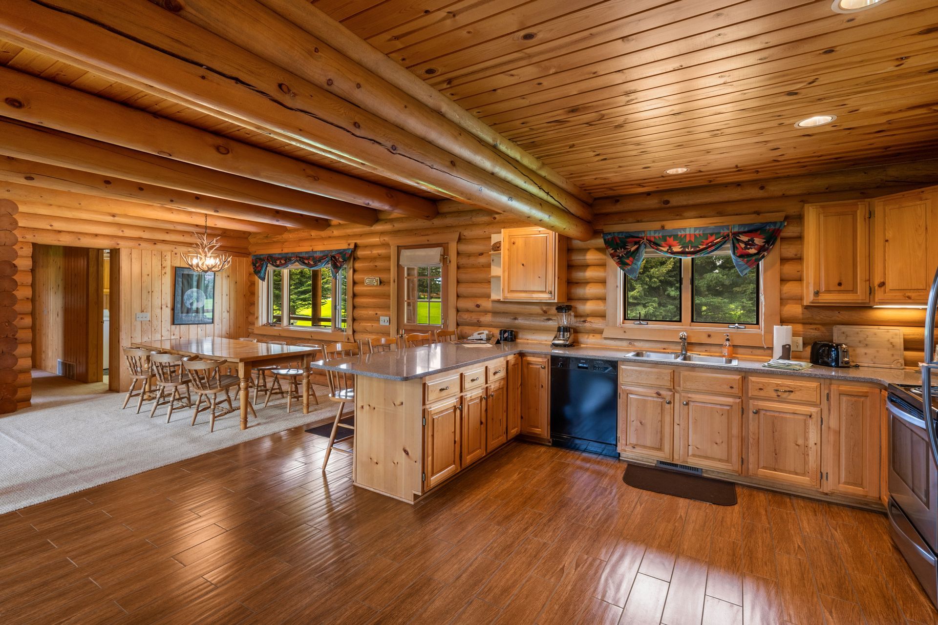 A kitchen in a log cabin with wooden cabinets and stainless steel appliances.