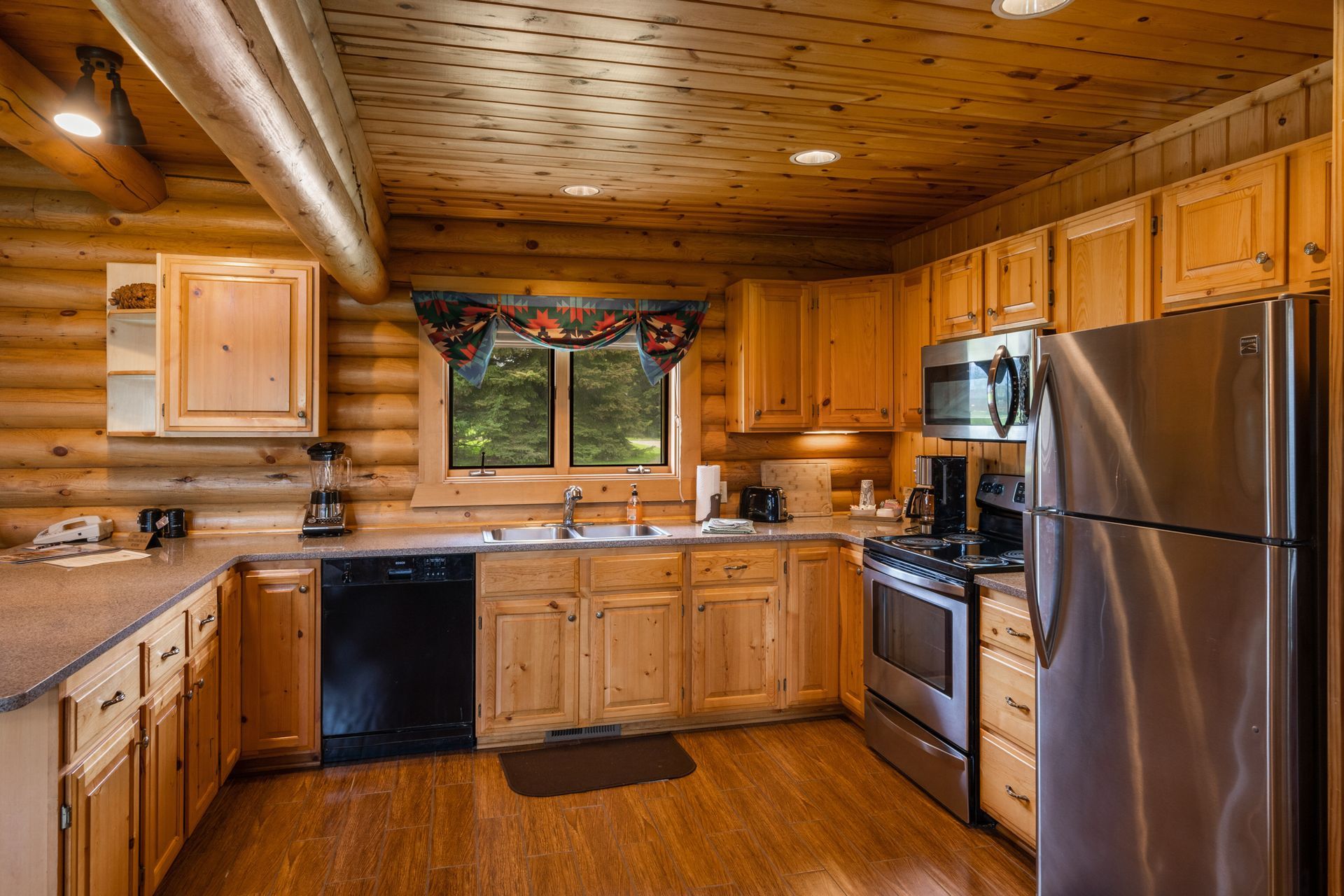 A kitchen in a log cabin with stainless steel appliances and wooden cabinets.