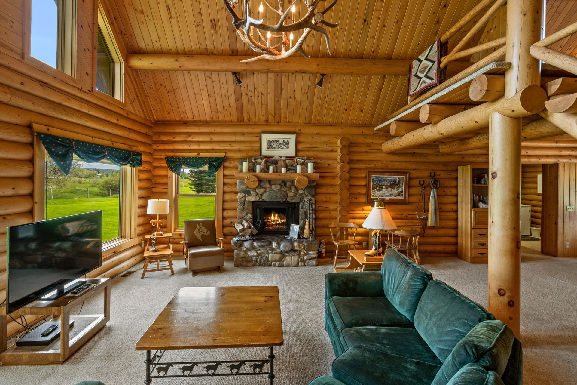 A living room in a log cabin with a couch , fireplace and television.