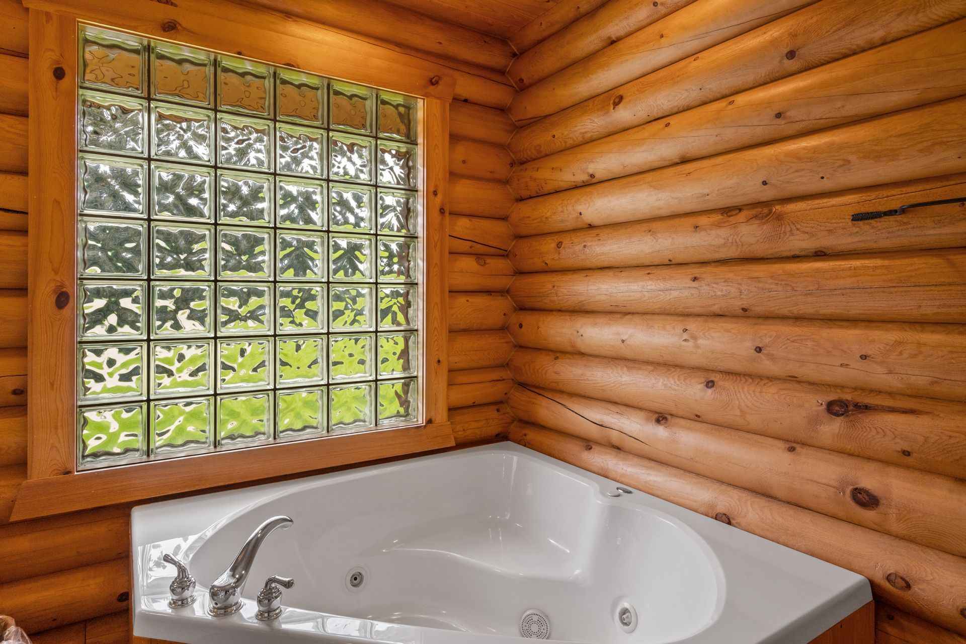 A bathroom in a log cabin with a jacuzzi tub and a window.