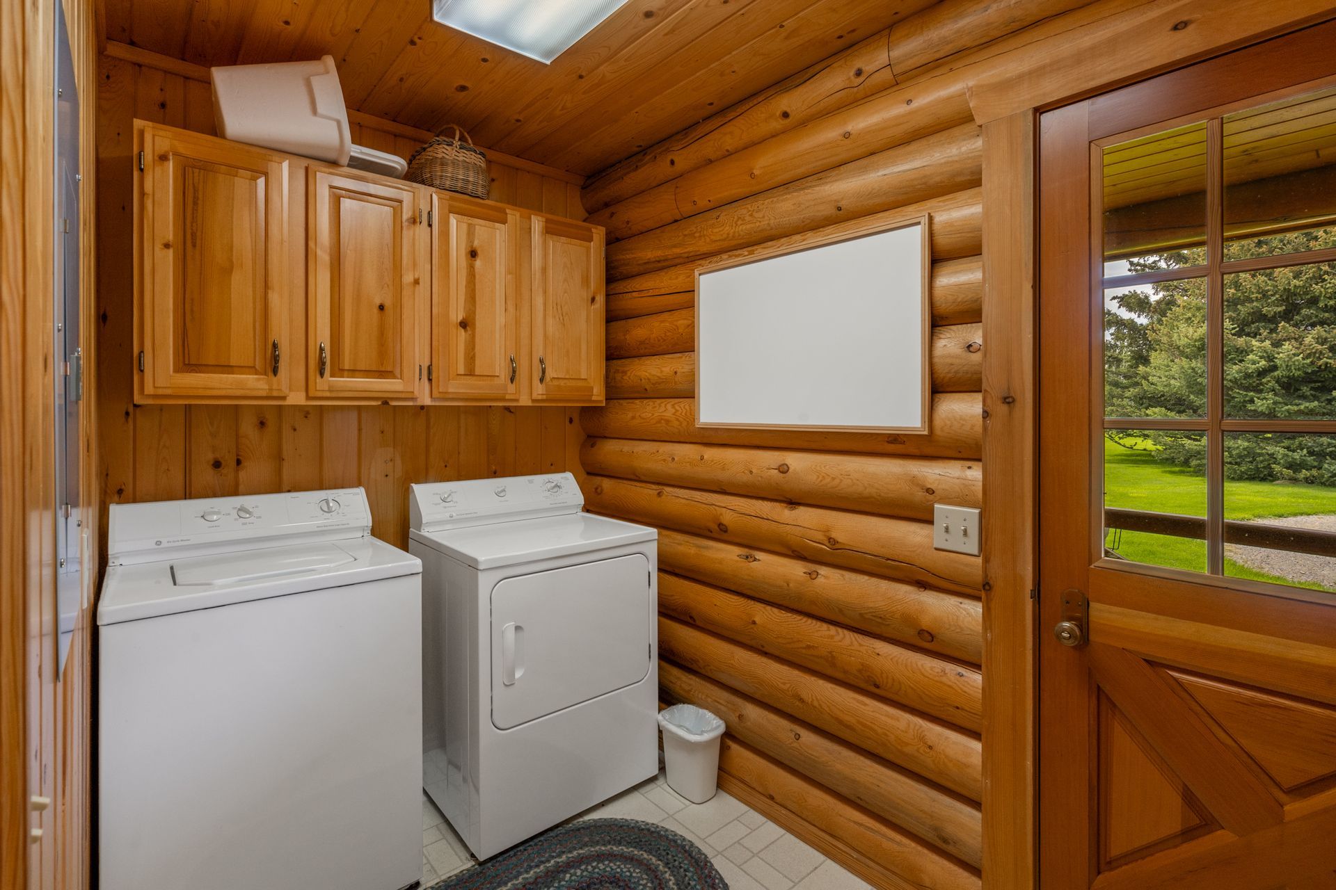 A laundry room in a log cabin with a washer and dryer.