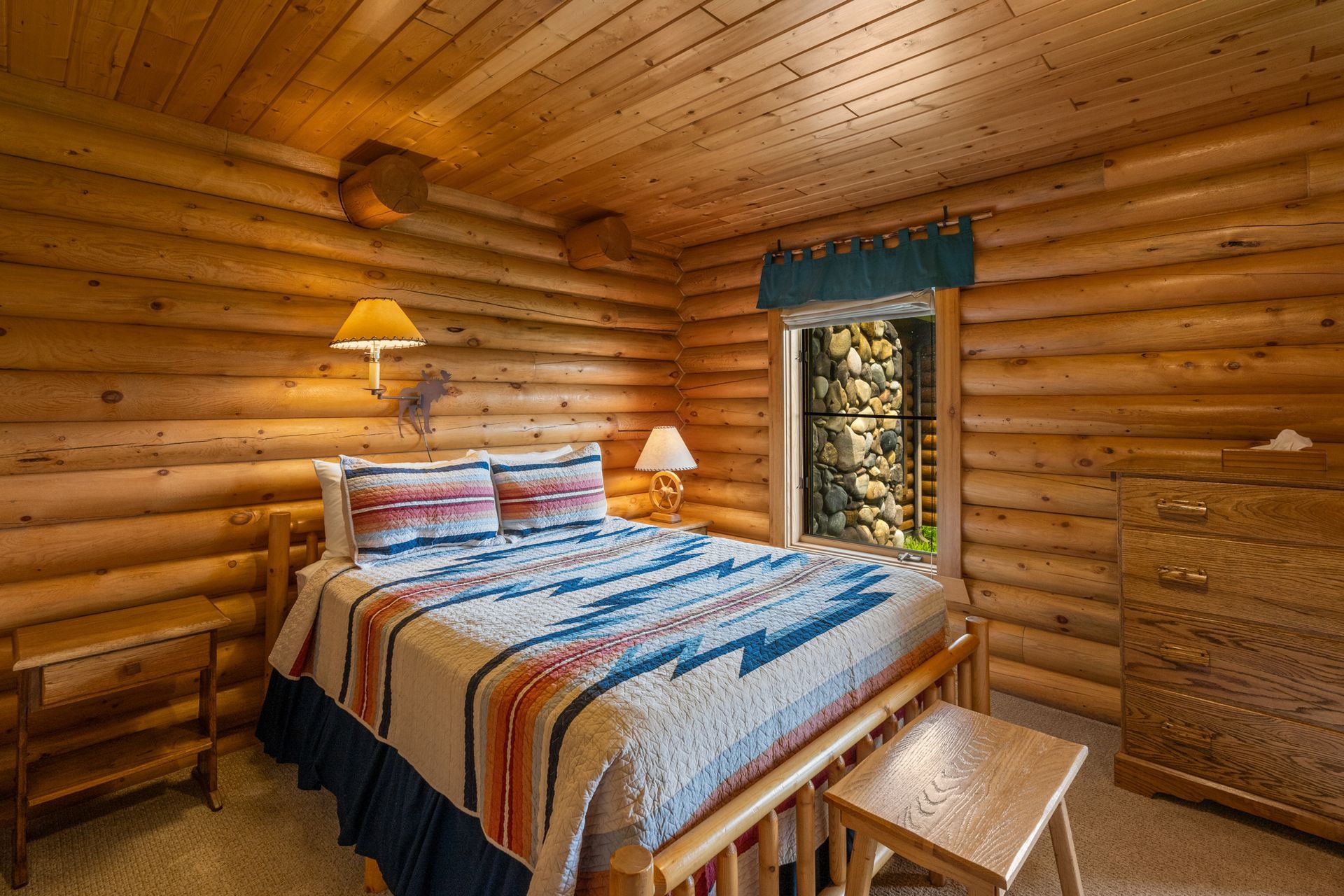 A bedroom in a log cabin with a king size bed and a dresser.