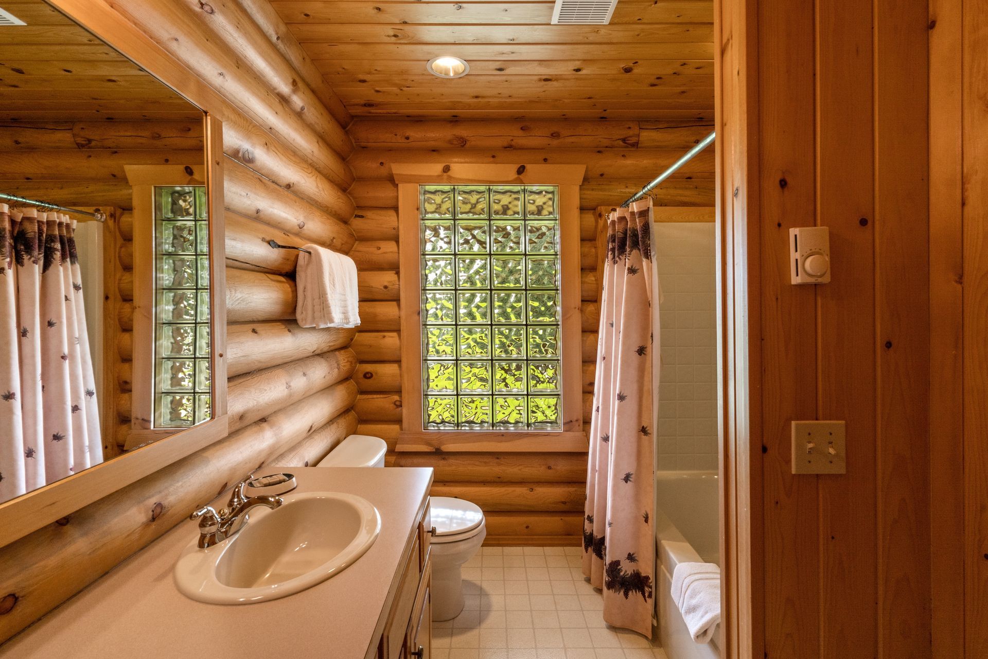 A bathroom in a log cabin with a sink , toilet and shower.