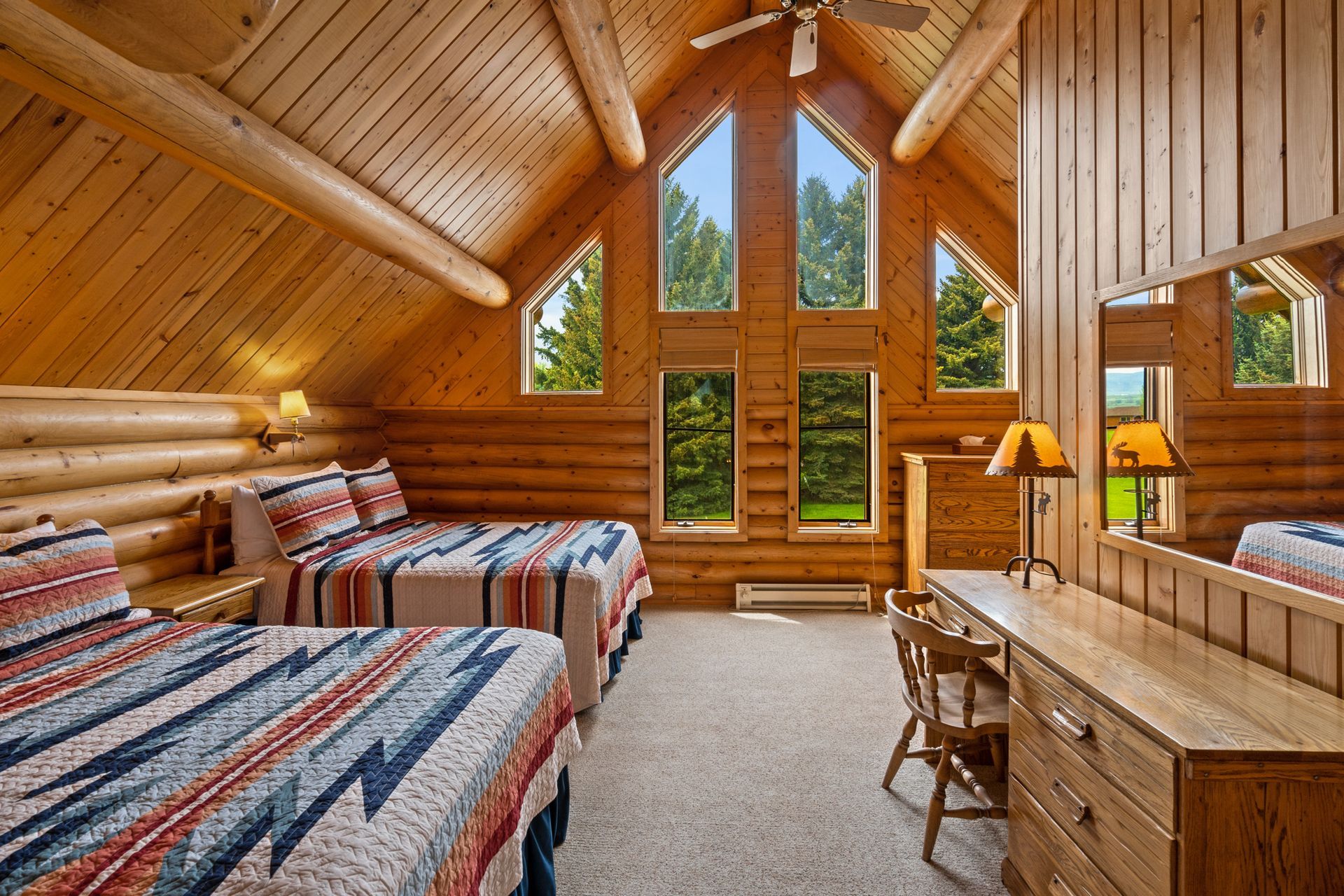 A bedroom in a log cabin with three beds and a dresser.