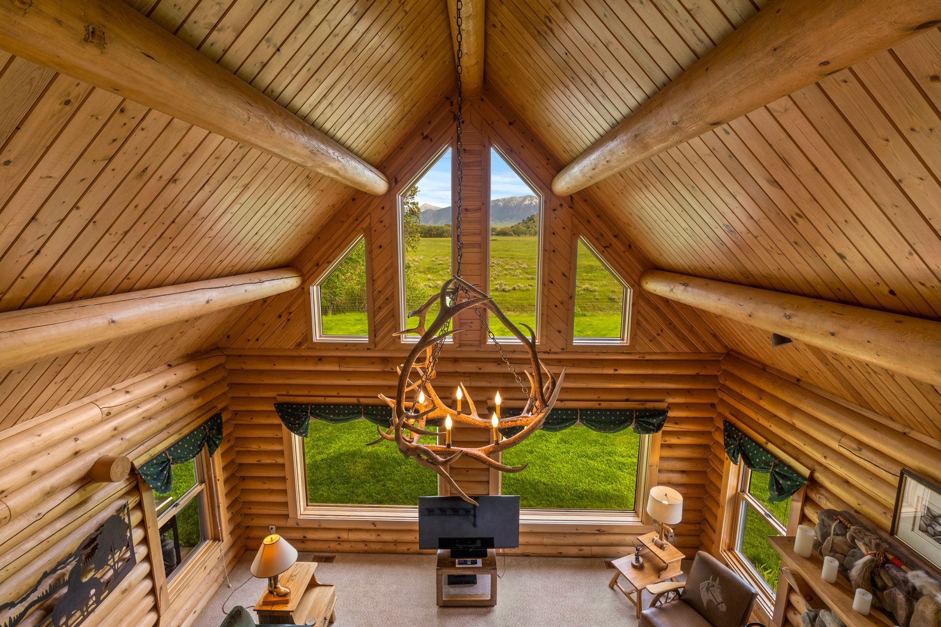 A living room in a log cabin with a chandelier hanging from the ceiling.