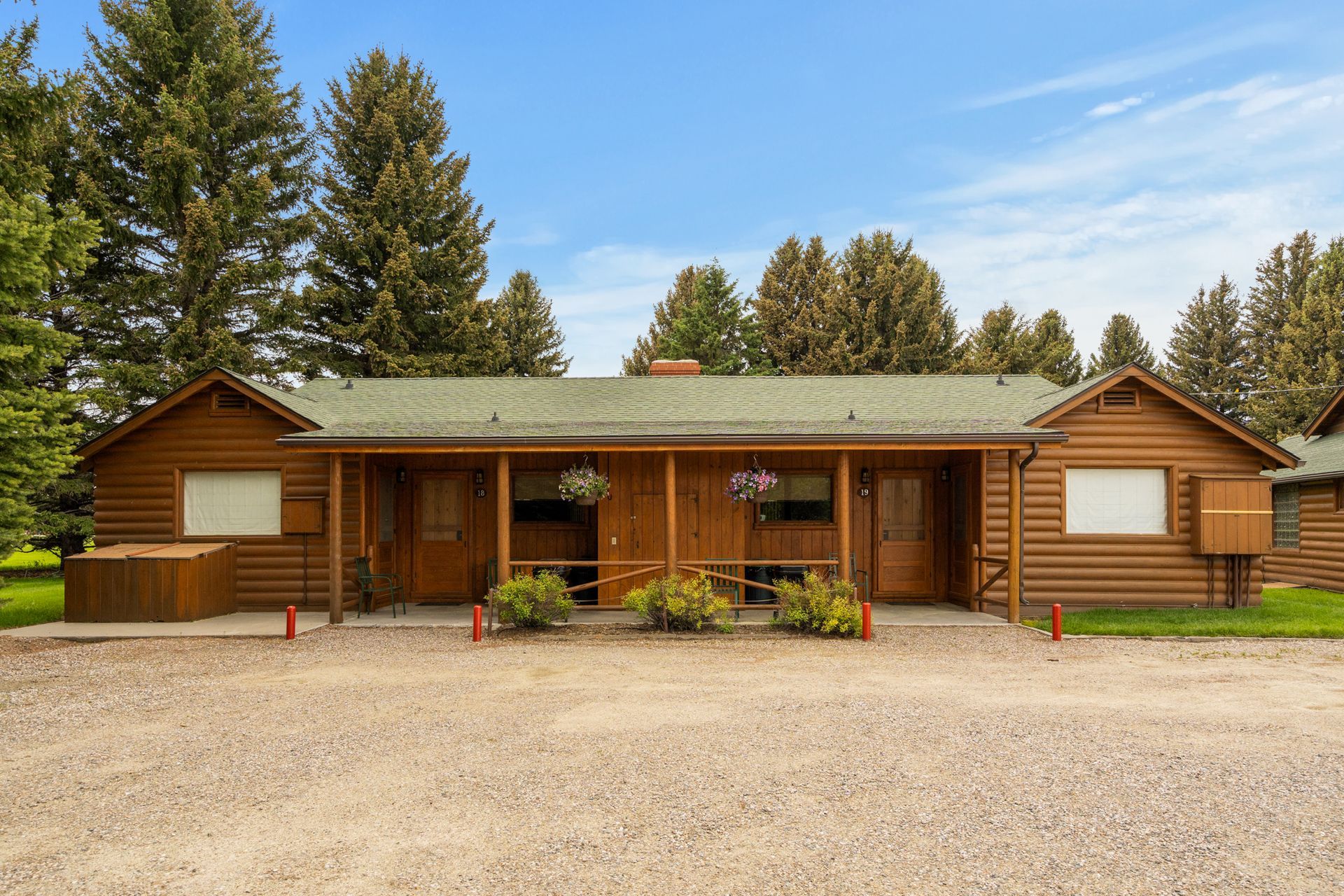 A large wooden house with a green roof is surrounded by trees.