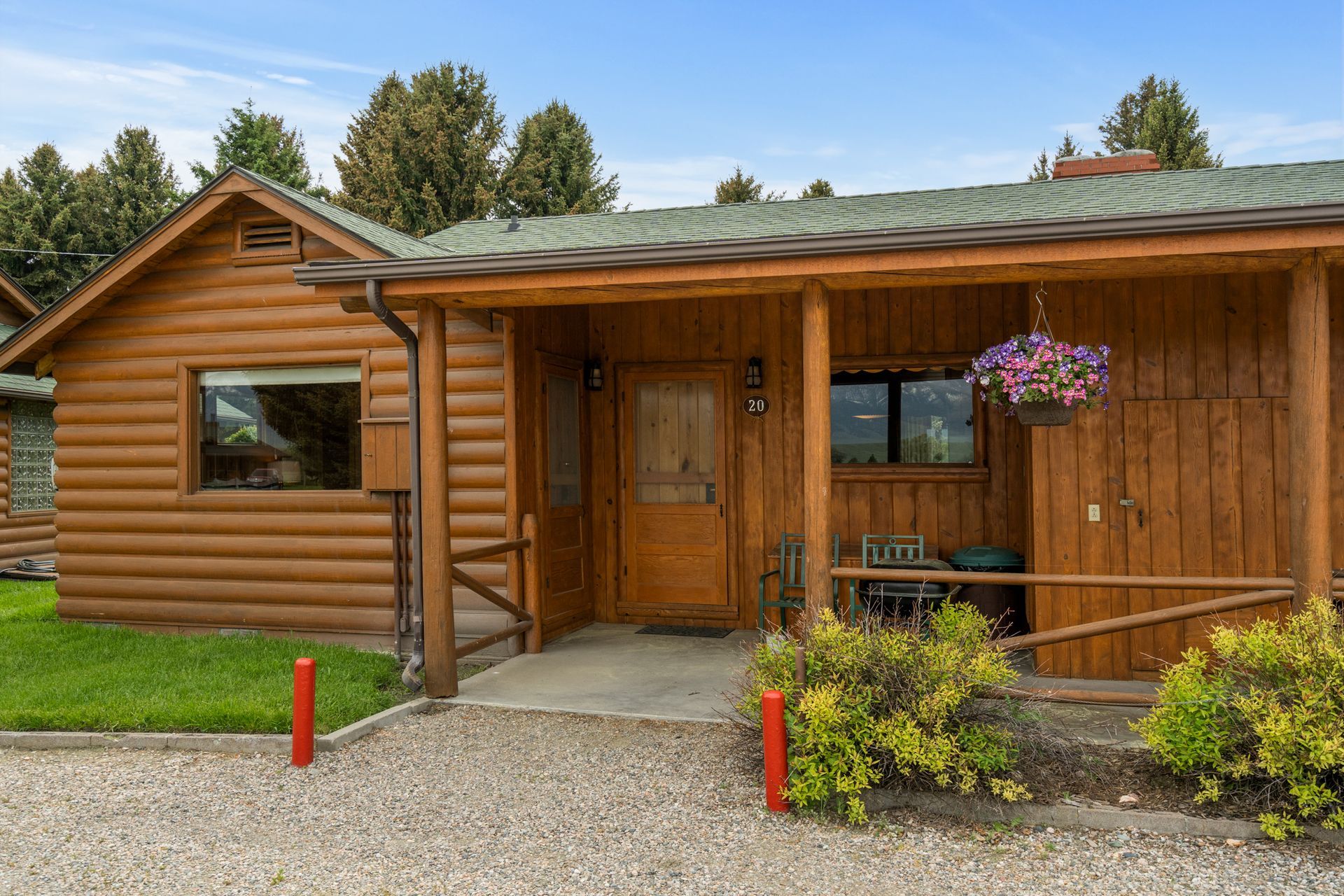 A small log cabin with a porch and flowers on it.