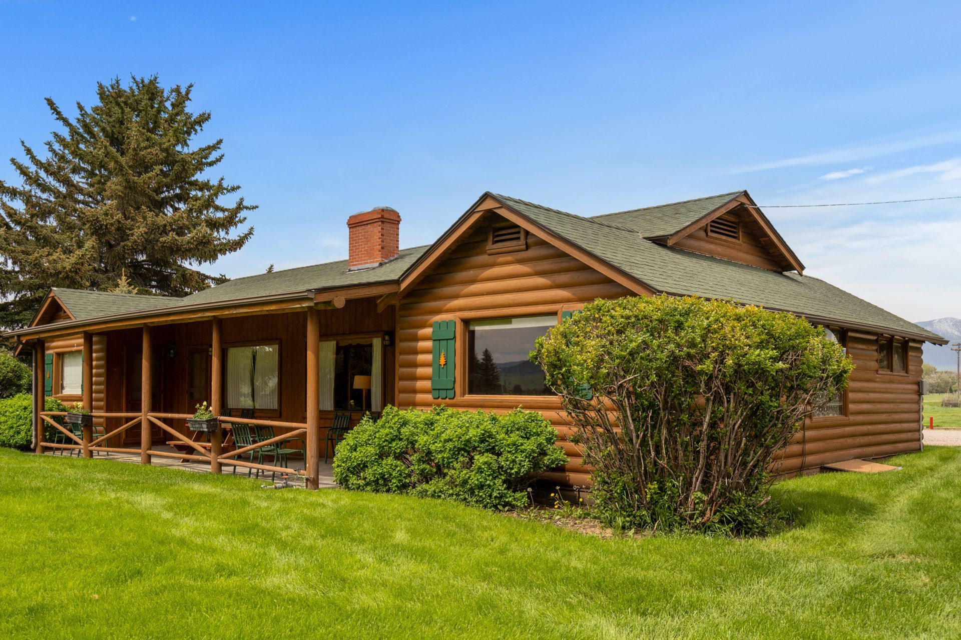 A log cabin with a green roof and a porch