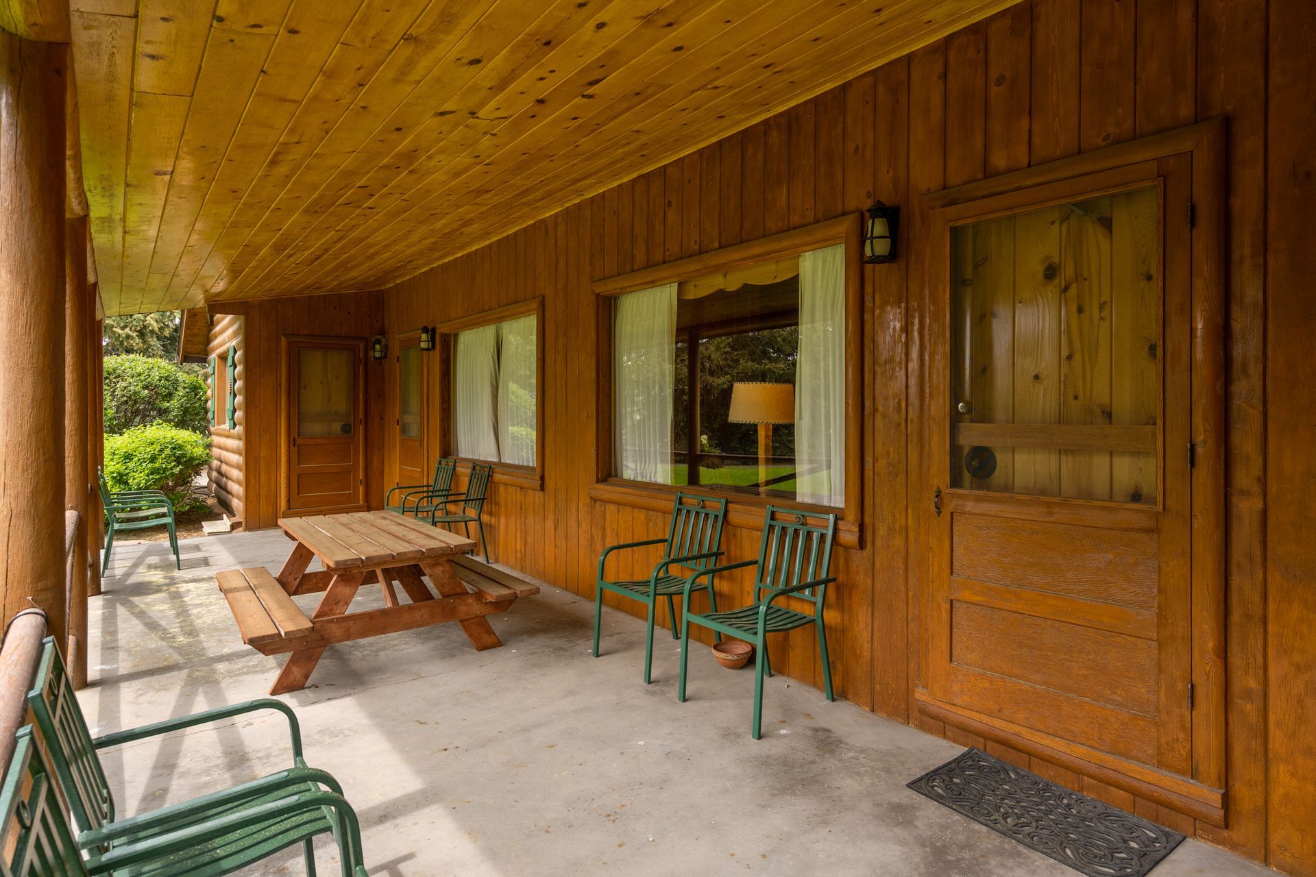 There is a porch with a picnic table and chairs on it.