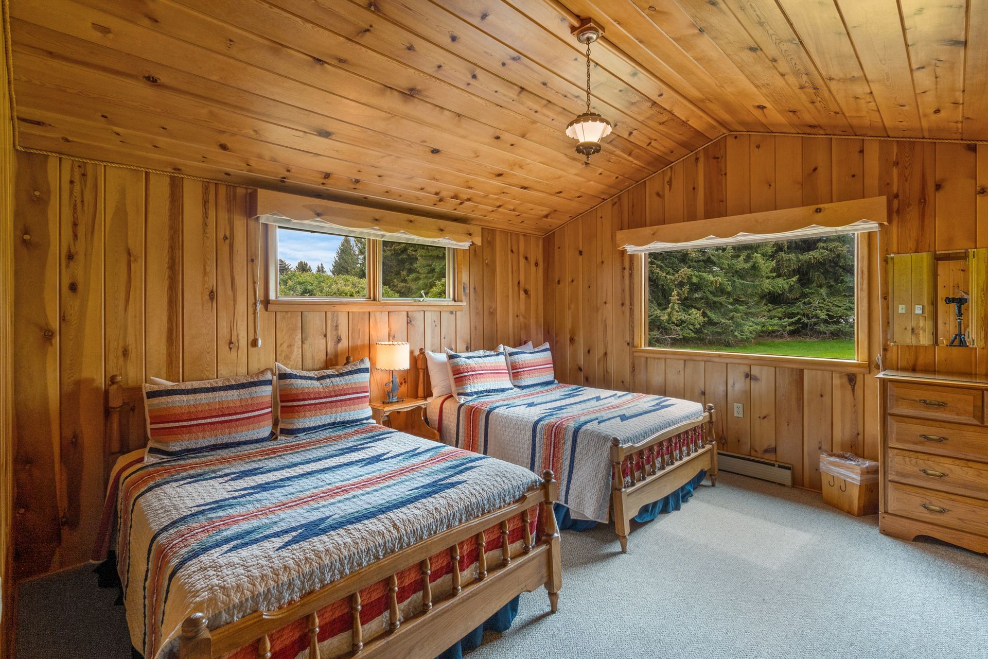 A bedroom with two beds and a window with a view of a forest.