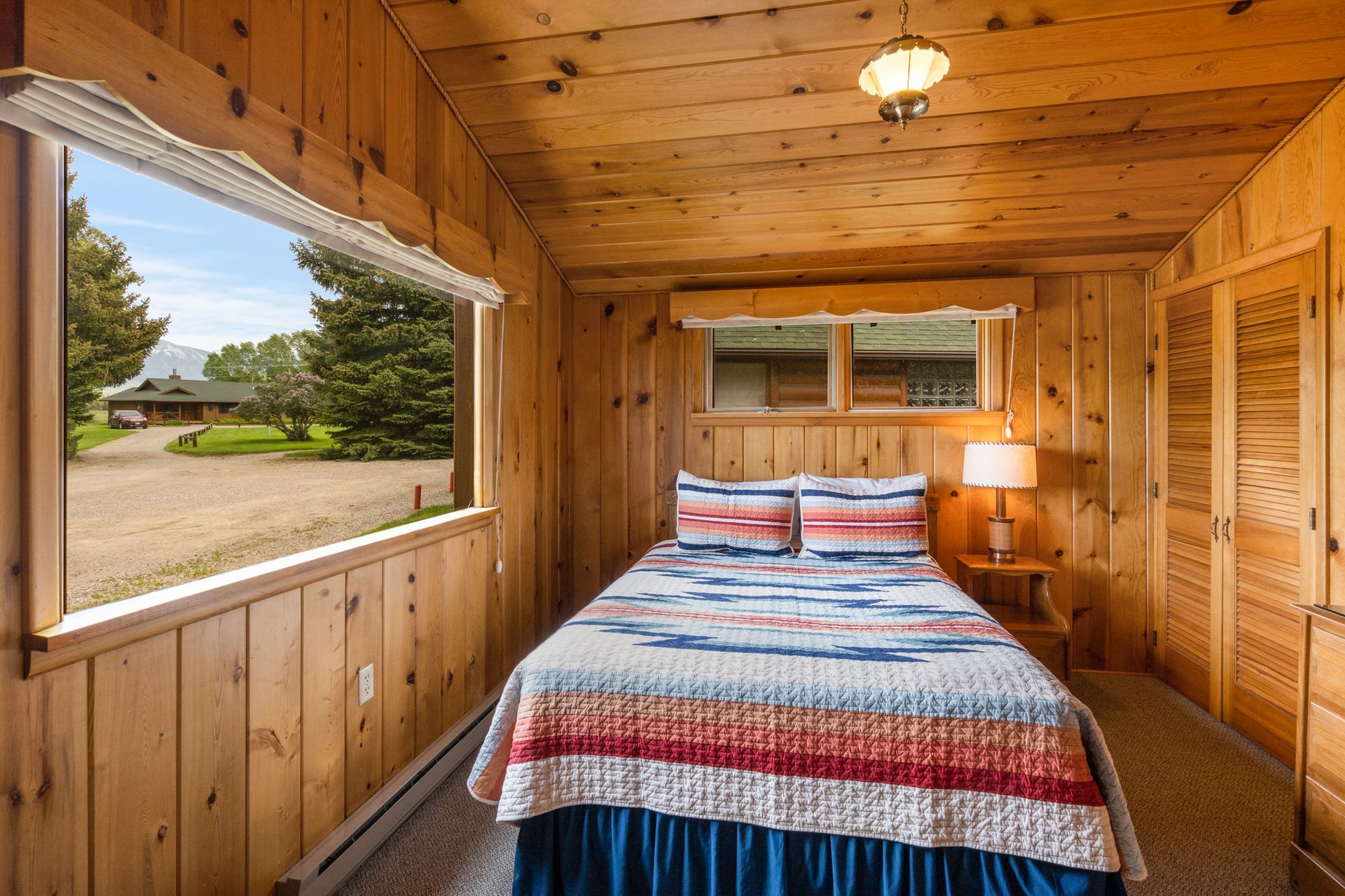 A bedroom in a log cabin with a bed and a window.