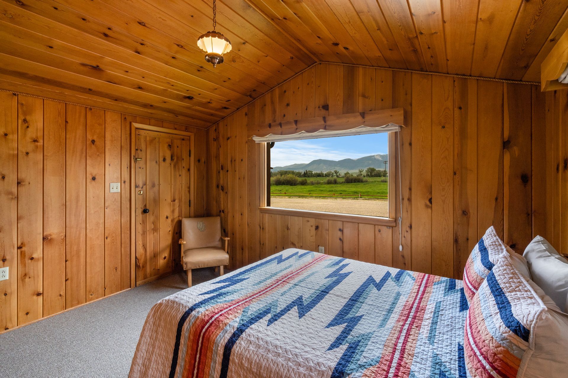 A bedroom with a bed , chair and window with a view of a field.