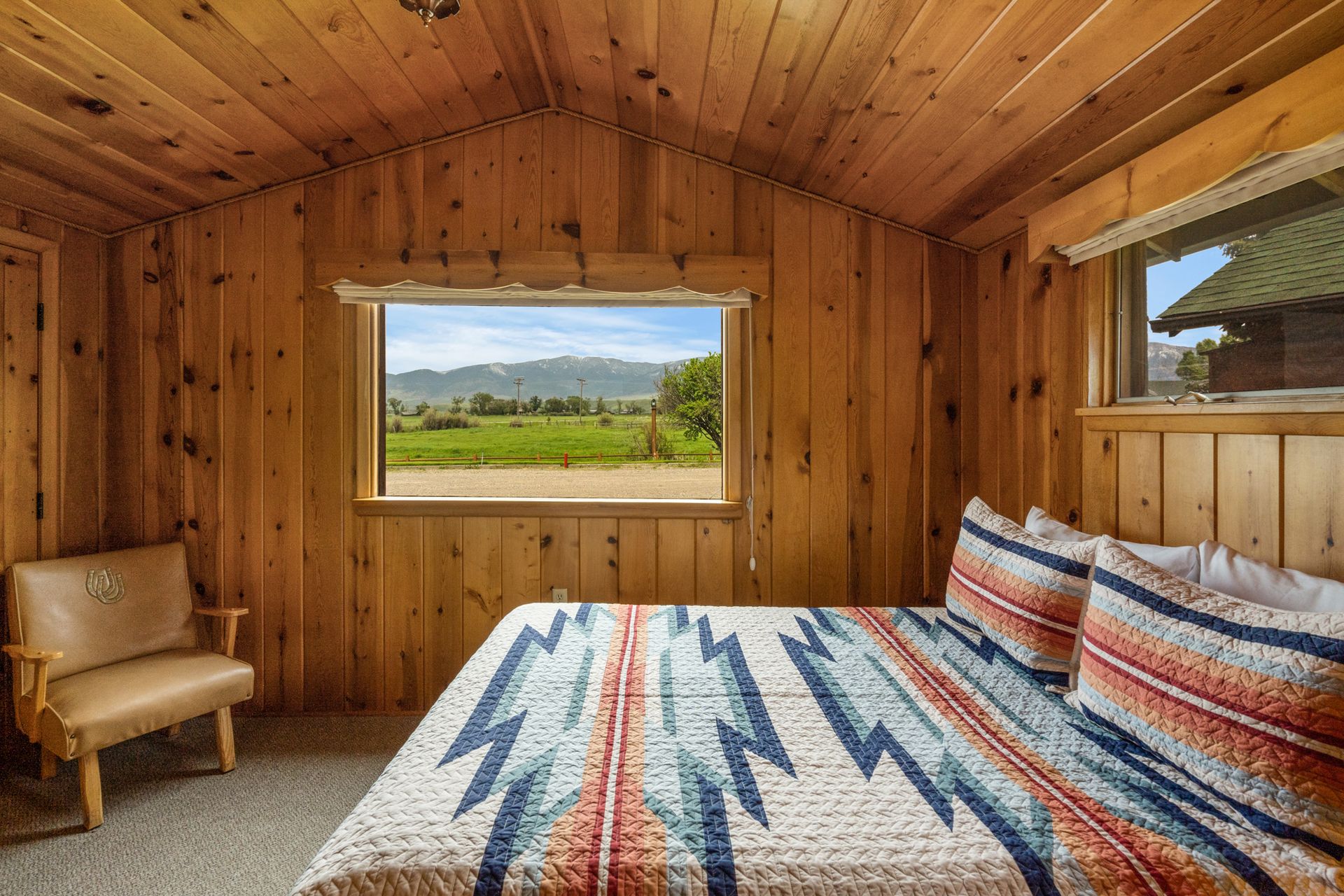 A bedroom with a bed , chair and window with a view of a field.