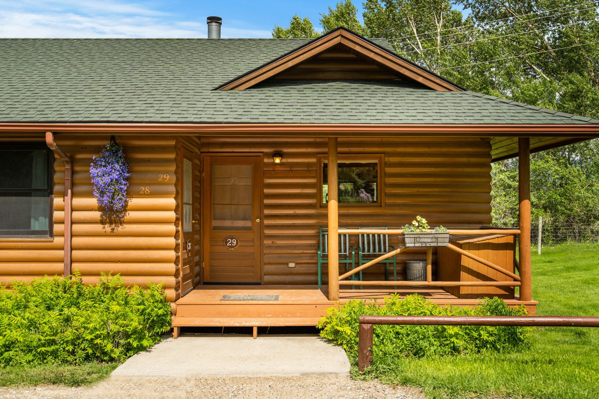 A small log cabin with a porch and a green roof.