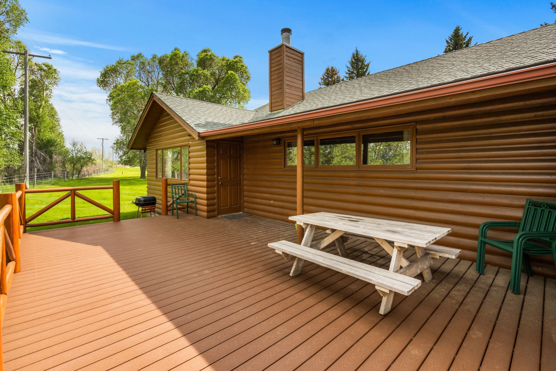 There is a picnic table on the deck of a log cabin.