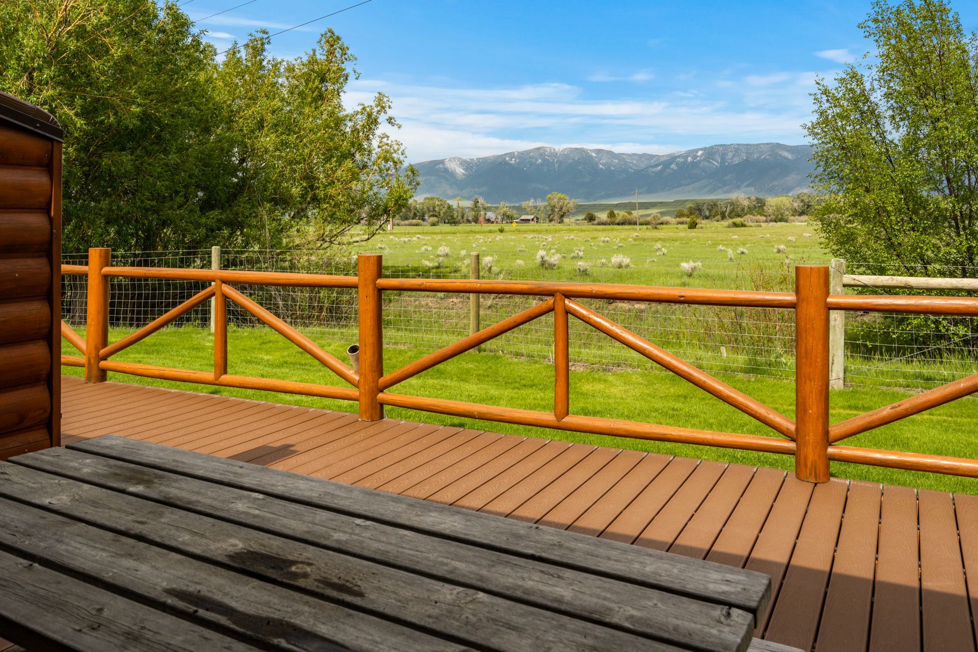 A wooden deck with a wooden fence and a view of a field.