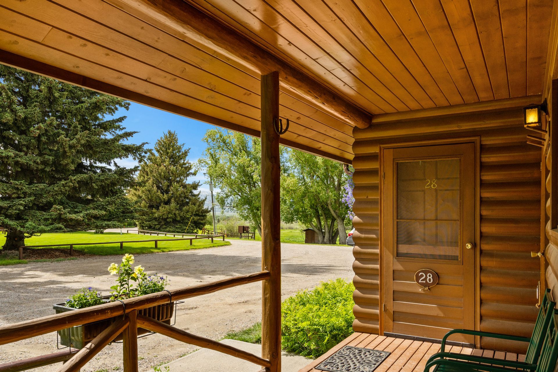 A porch of a log cabin with trees in the background