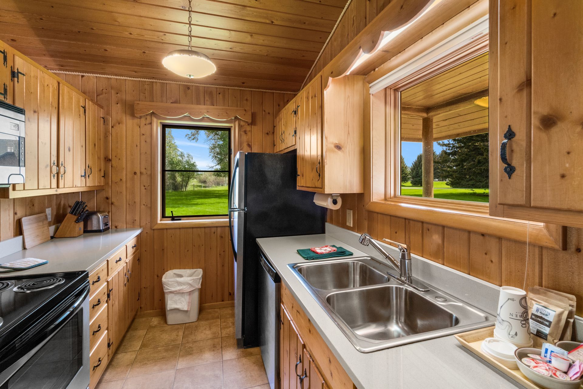 A kitchen with wooden cabinets , stainless steel appliances , a sink and a refrigerator.