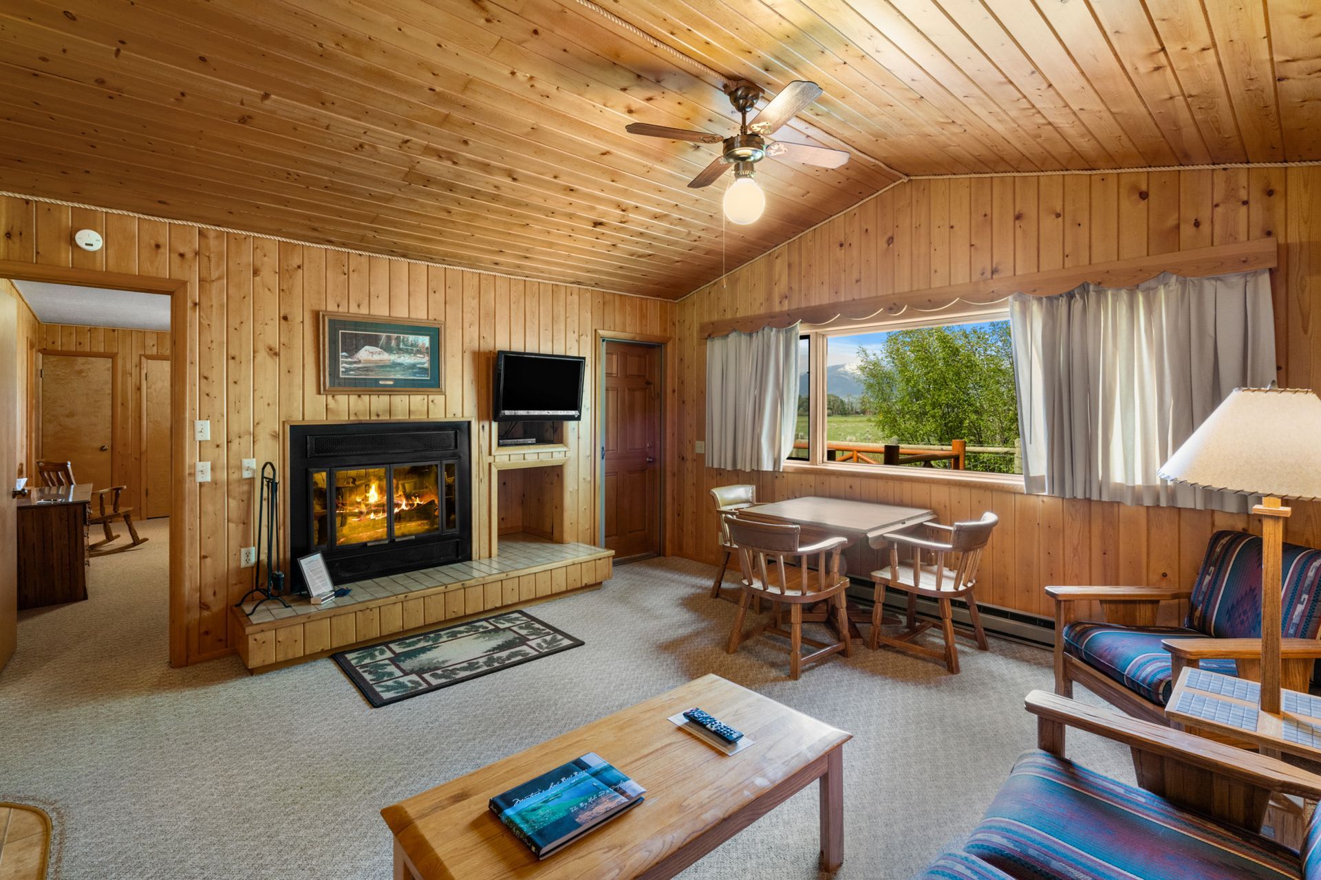 A living room with a fireplace , chairs , a table and a television.