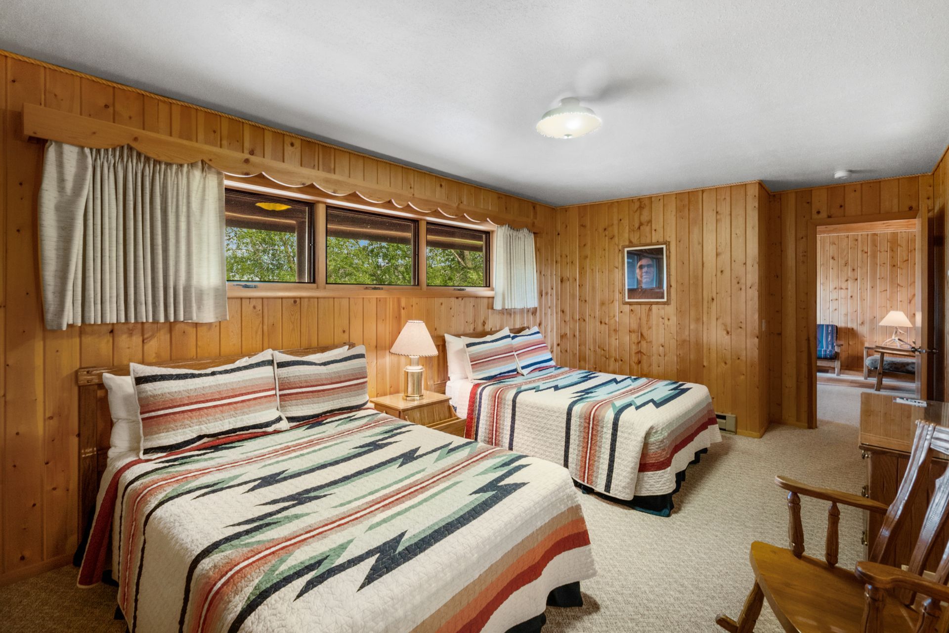 A bedroom with two beds and a rocking chair.