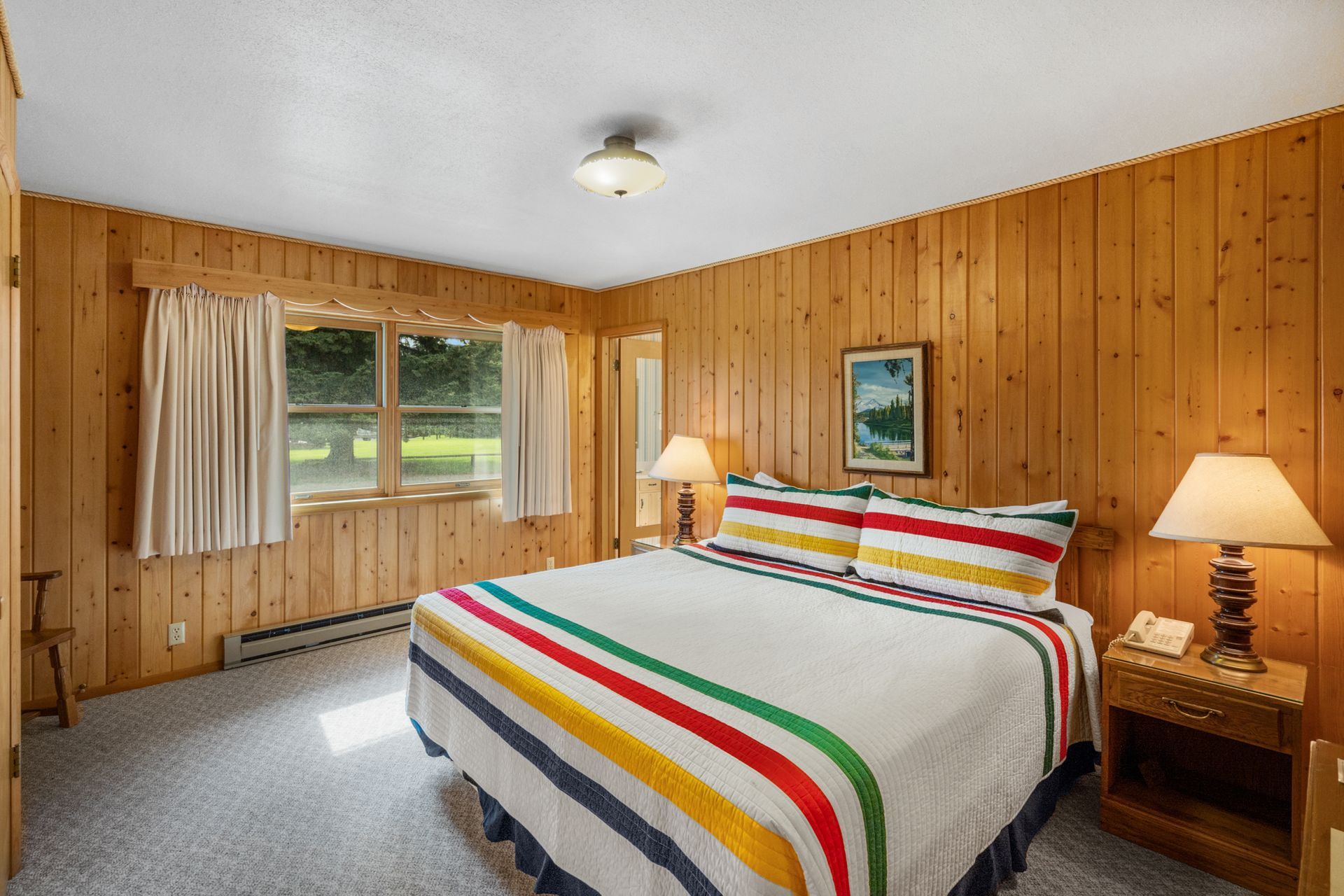 A bedroom with a king size bed and wood paneling