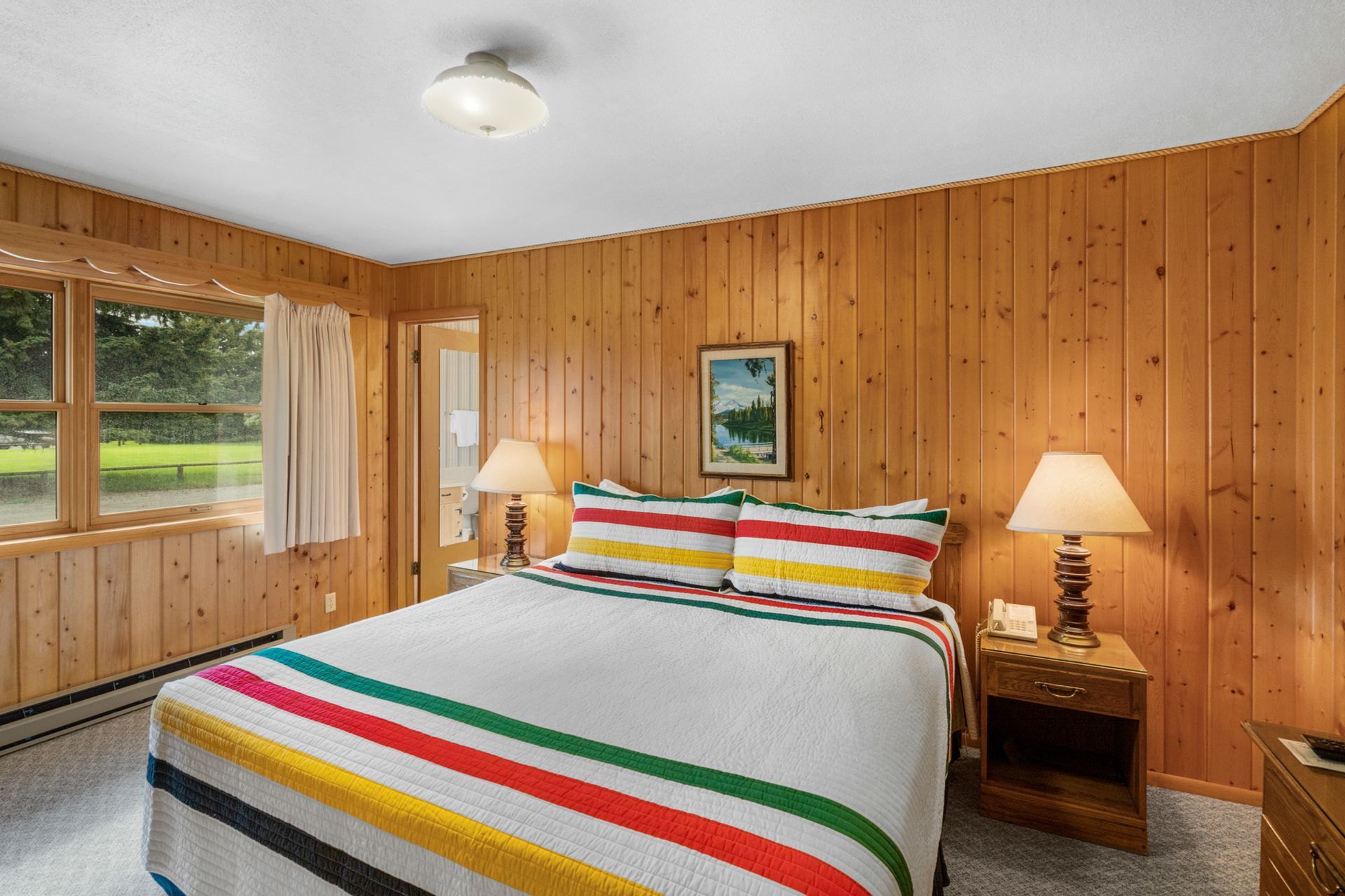 A bedroom with a king size bed and wood paneled walls.