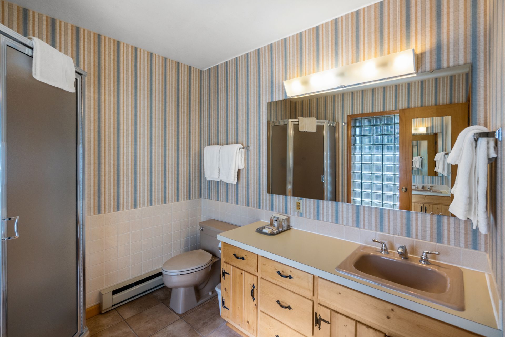 A bathroom with a toilet , sink , mirror and shower.