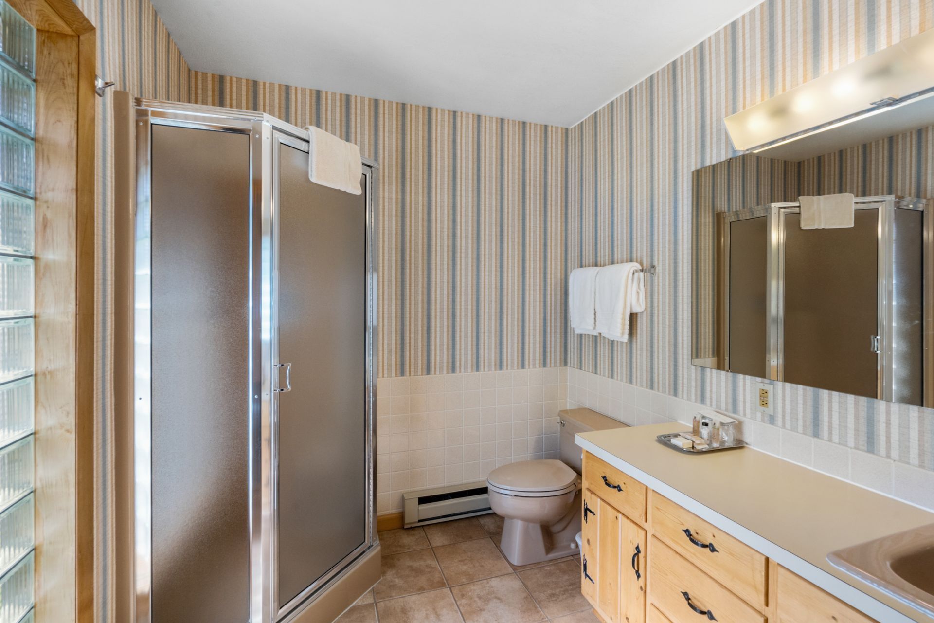 A bathroom with a toilet , sink , shower and mirror.