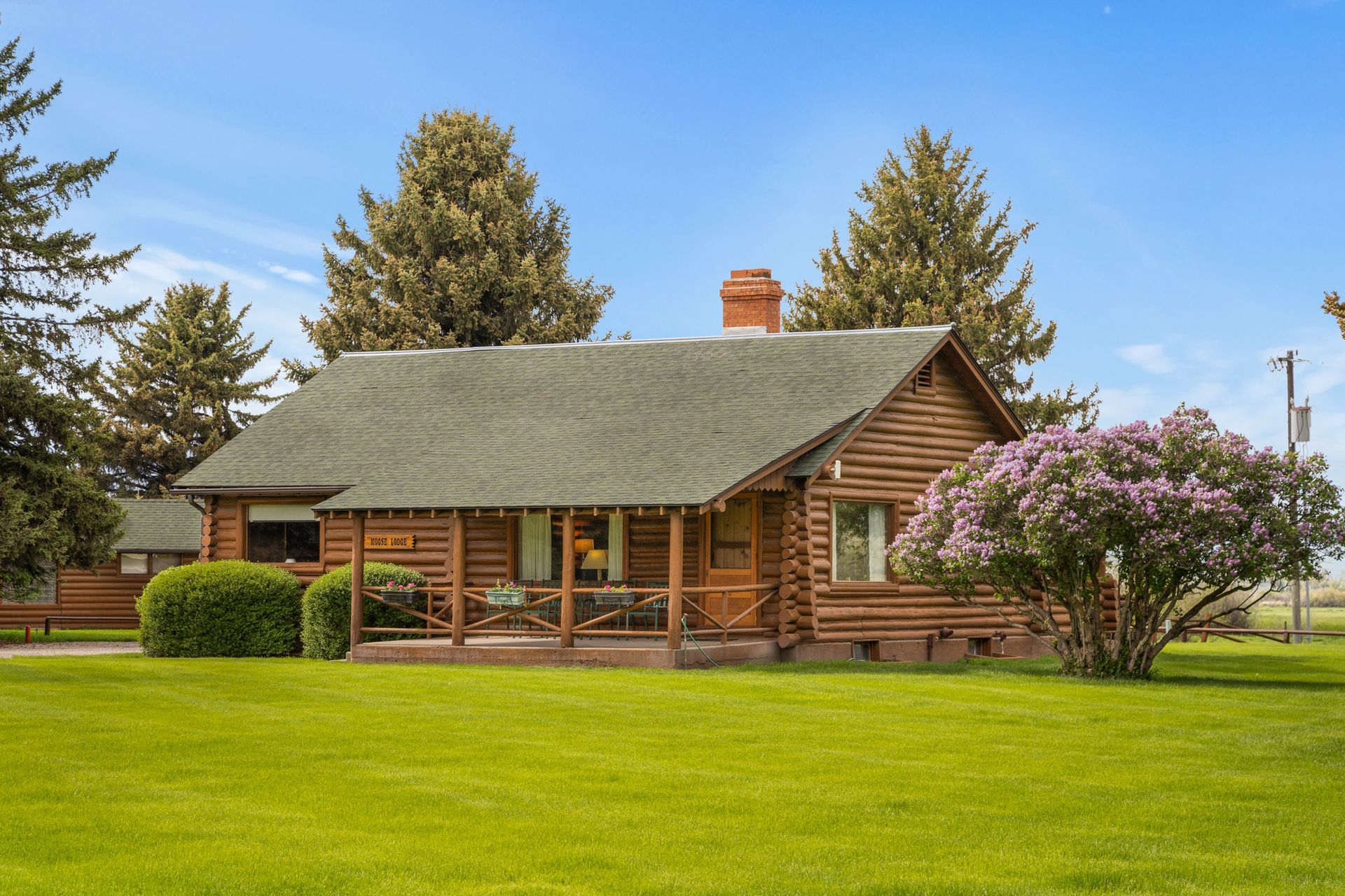 A log cabin is sitting in the middle of a lush green field.