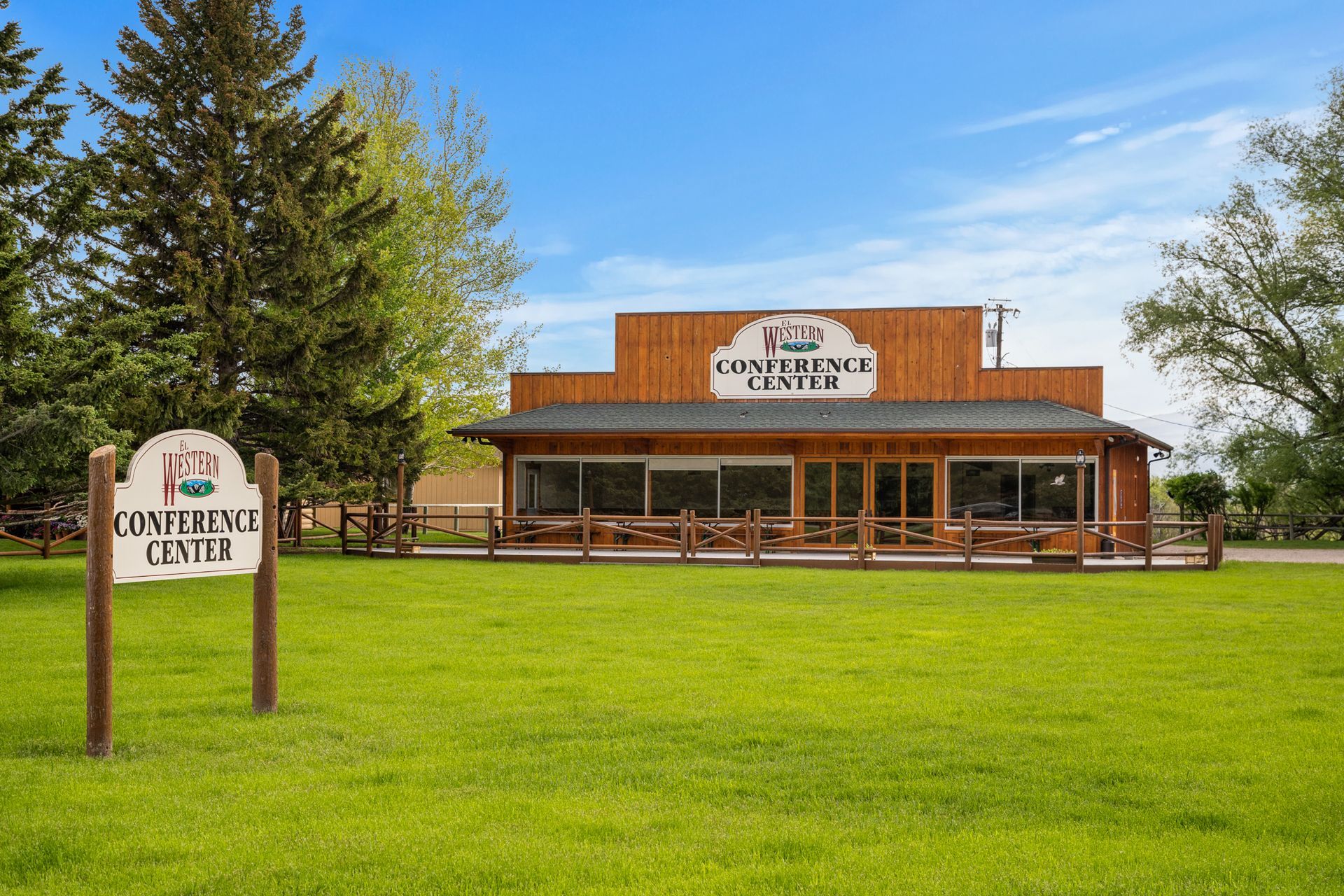 A large wooden building is sitting in the middle of a grassy field.